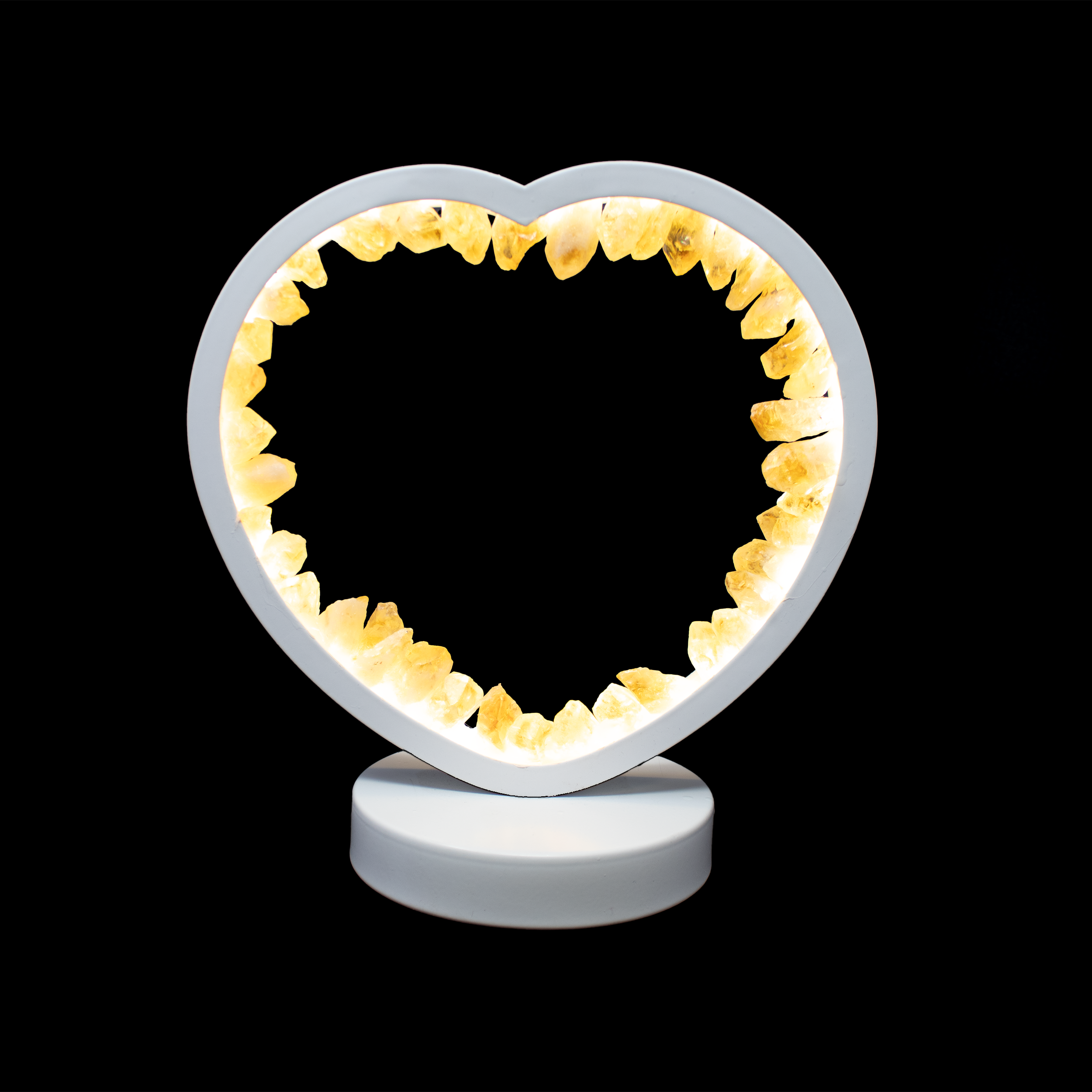Polished to a warm golden glow, the Citrine Crystal Heart Luminary radiates gentle light and natural positivity. Carved from genuine citrine and fitted with a white LED cord, this sculptural heart casts a soft, ambient glow—an inviting presence on a nightstand, meditation altar, or shelf. The natural inclusions and honeyed tones of each crystal make every piece one-of-a-kind, blending luminous charm with grounding beauty.Known as a stone of abundance and joy, citrine carries an uplifting energy that complements its comforting warmth. Whether given as a heartfelt gift or kept as a personal talisman of light and love, this crystal heart luminary adds both serenity and sentiment to any space. Citrine Crystal Heart Luminary with White Light & Cord