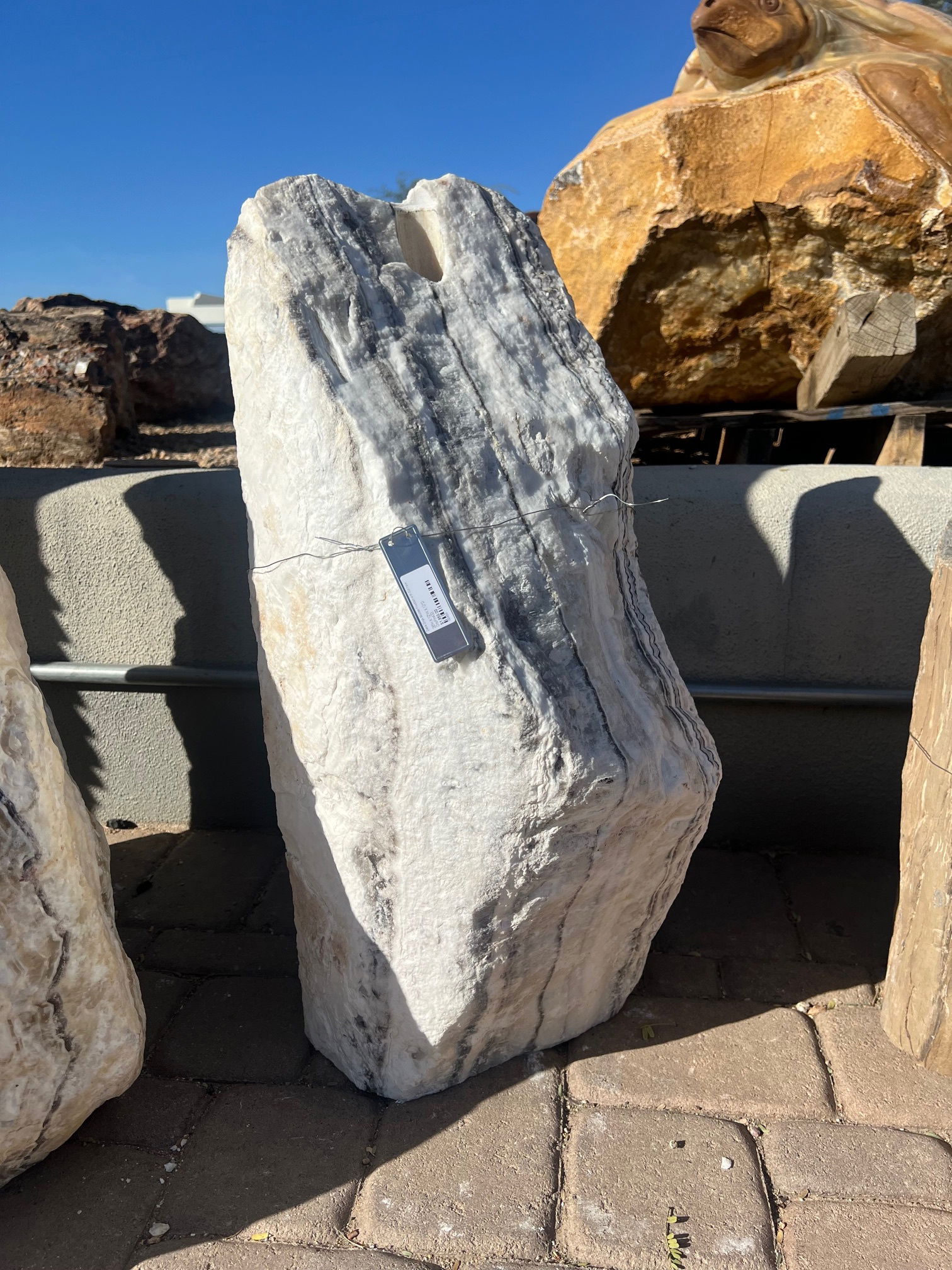 Introducing the Zebra Onyx Boulder Fountain with Cut Face and Sterling Accents–an exquisite masterpiece that brings the elegance of natural stone and the soothing sound of flowing water into your space. This distinctive fountain is crafted from premium zebra onyx, known for its striking patterns and rich tones that mirror the majestic beauty of the wild. The innovative cut face design reveals the intricate layers and unique markings of the onyx, enhancing its natural allure. Let Rare Earth Gallery’s white-glove service make your fountain dreams come true—simply choose your fountain, tell us where it goes, and we’ll handle the rest, from delivery to installation. IMPORTANT: the purchase price listed is for the FOUNTAIN ONLY and DOES NOT INCLUDE the cost of a basin, pump, parts or installation. Before purchasing a fountain online, we STRONGLY recommend you call us at (480) 575-4360 for a FREE consultation to discuss these additional costs and schedule a pre-site inspection. Also, free shipping does NOT apply to fountains, please call for a quote. Zebra Onyx Boulder Fountain With Cut Face