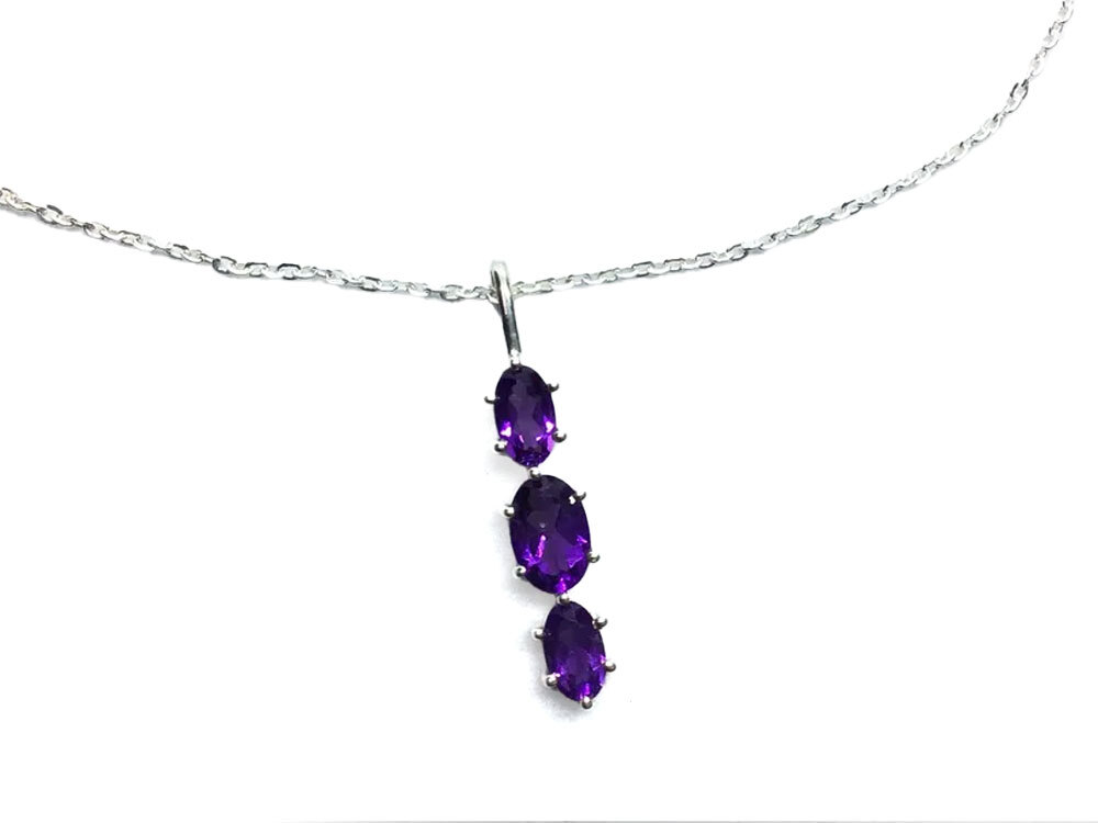 Radiate elegance with our Faceted Amethyst Necklace, featuring three dazzling oval-cut amethysts intricately prong-set in genuine 925 sterling silver. Each gemstone catches the light with breathtaking brilliance, suspended on a classic 18-inch chain for timeless sophistication. Perfect for everyday wear or special occasions, this necklace celebrates the natural beauty of amethyst—known for its calming and empowering energies. Faceted Amethyst Necklace - 3 Faceted Ovals Prong Set with 925 Sterling Silver with 18" Chain