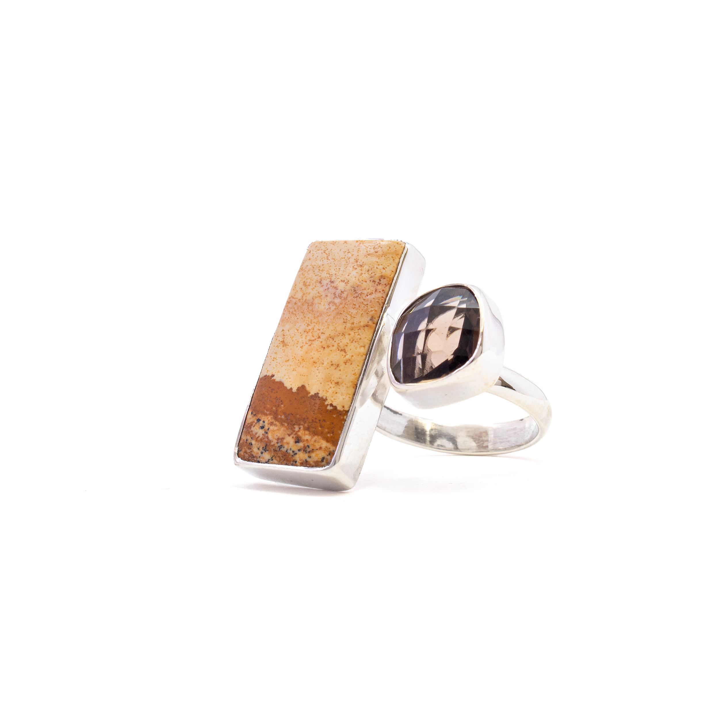 Introducing our exquisite Picture Jasper Ring, a statement piece that captures the beauty of nature in polished stone and refined metal. This unique ring features a stunning rectangle cabochon of Picture Jasper, known for its earthy tones and intricate patterns resembling abstract landscapes. Complementing this centerpiece is a captivating faceted smoky quartz, set in a freeform design that adds an element of sophistication and sparkle.Crafted from premium 925 sterling silver, the open band design ensures durability and timeless elegance while offering size adjustability for a perfect fit on any finger. The combination of natural stones and sterling silver creates a versatile piece that can effortlessly elevate both casual and formal outfits. Picture Jasper Ring - Rectangle Cabochon with Faceted Smoky Quartz Freeform Set on 925 Sterling Silver Open Band szAdj