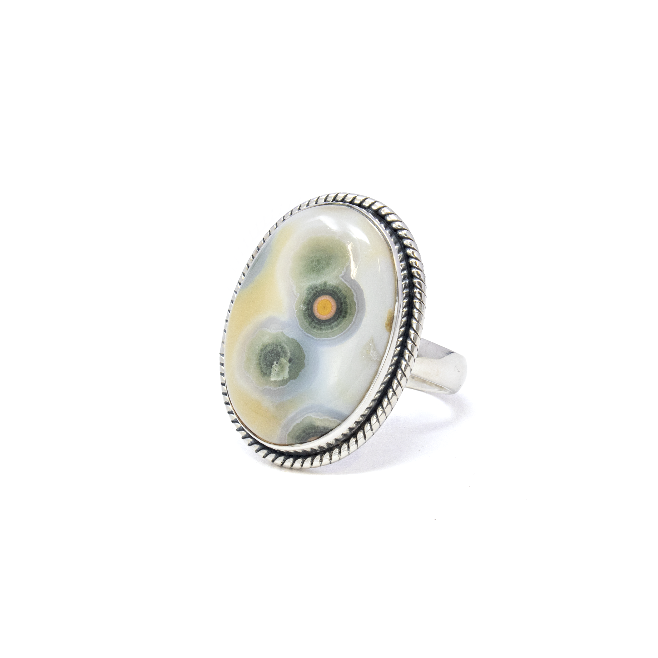 Immerse yourself in the captivating beauty of the sea with our exquisite Ocean Jasper Ring. This stunning piece showcases an oval cabochon Ocean Jasper gemstone, known for its mesmerizing patterns and serene, earthy hues. Each stone is unique, offering a one-of-a-kind creation that captures the essence of nature's artistry.The Ocean Jasper is elegantly set within a 925 sterling silver bezel, known for its durability and radiant shine. The bezel is meticulously crafted with a rope stamped edge, adding a touch of vintage charm and enhancing the organic allure of the gemstone. This thoughtful detailing exudes elegance and sophistication, making it a perfect addition to any jewelry collection. Ocean Jasper Ring - Oval Cabochon Set in 925 Sterling Silver Bezel with Rope Stamped Edge sz8