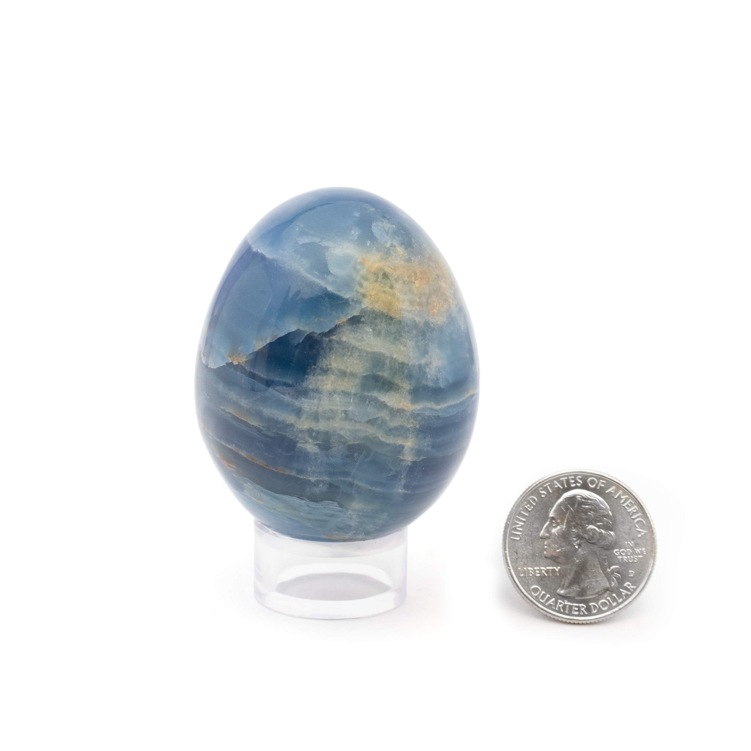 Elevate your collection of crystals and minerals with this exquisite A+ Argentinian Blue Calcite Egg, a true masterpiece of nature displayed with utmost elegance. Mined from the renowned mineral-rich regions of Argentina, this blue calcite egg is coveted for its soothing color and unique geometric shape, representing serenity and balance.This calcite egg boasts an A+ grade, ensuring its top-tier quality and impressive visual appeal. Its smooth, polished surface enhances its natural luster, showcasing the crystal's calming hues of soft blues and subtle whites. The egg shape, a symbol of new beginnings and transformation, complements the calming energy of blue calcite. It's ideal for those who cherish the natural beauty and healing properties of crystals. A+ Argentinian Blue Calcite Egg with Lucite Ring Stand