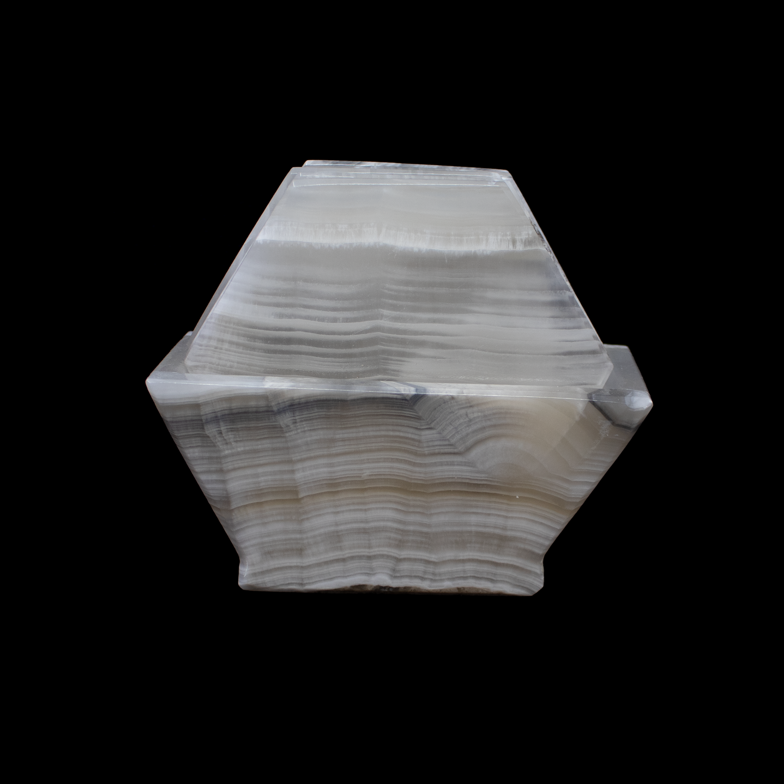 Add refined beauty to your tabletop with this exquisite set of Banded Pearlescent Onyx Coasters. Each hexagonal piece is carved from genuine onyx, polished to reveal luminous pearlescent bands and natural earthy swirls. No two coasters are alike, making this set a true celebration of nature’s artistry.Designed to protect your surfaces while enhancing your decor, these substantial coasters handle both hot and cold beverages with ease. The modern geometric shape lends a sleek, contemporary feel, while the coordinating onyx holder keeps the set neatly organized and display-ready. Banded Pearlescent Onyx Coasters - Set of 6 with Holder - Hexagons