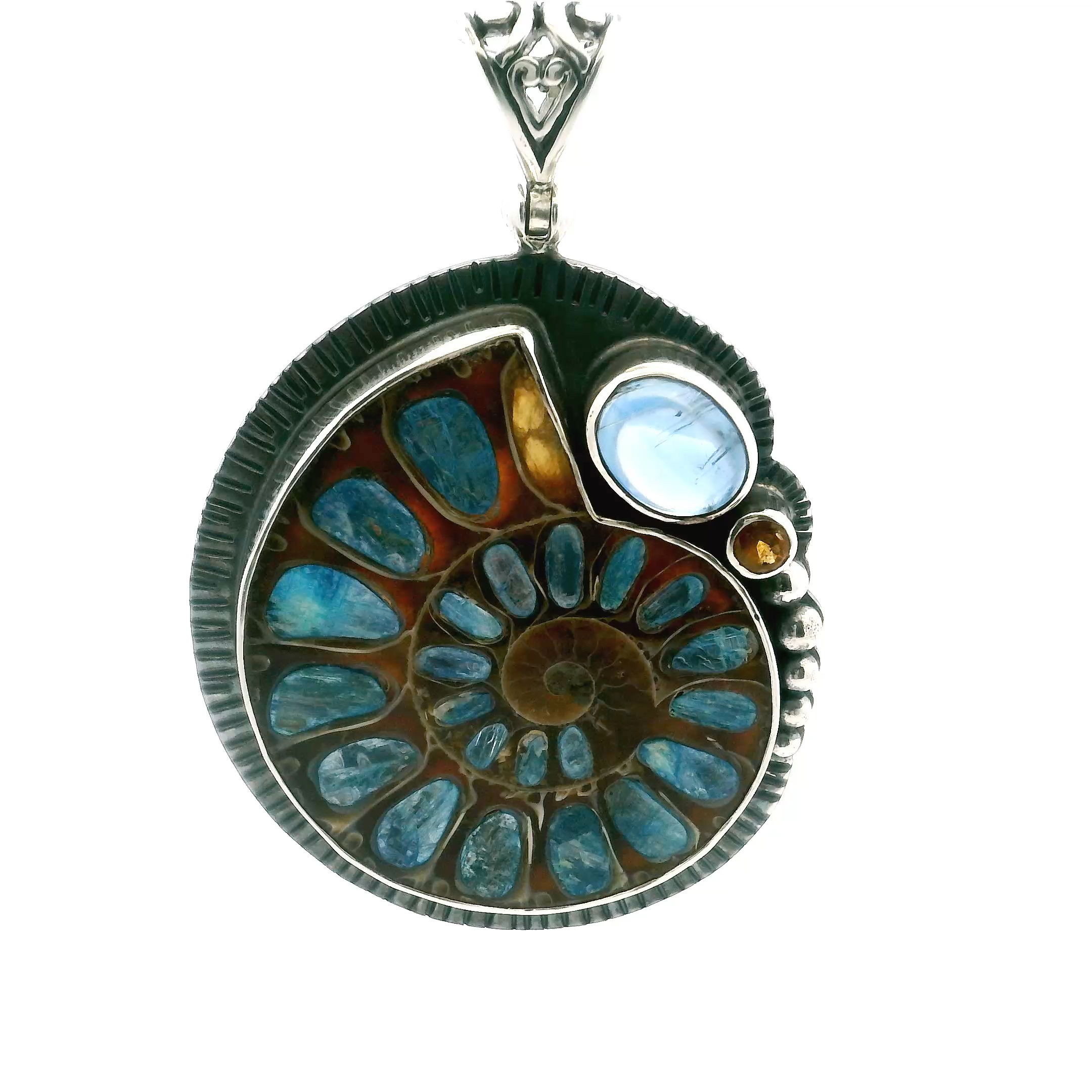Unveil Earth's ancient beauty with our Ammonite Fossil Pendant. Featuring an open ammonite cross-section inlaid with rich blue kyanite, this piece captures the spirit of prehistoric oceans. A luminous kyanite cabochon and a bezel-set faceted citrine add vibrant contrast and golden brilliance. Crafted in 925 sterling silver with intricate bead and line accents, this pendant blends natural wonder with timeless elegance—perfect for those who appreciate rare, meaningful jewelry. Ammonite Fossil Pendant - Open Ammonite Cross-section Inlaid with Kyanite with Kyanite Oval Cabochon and Faceted Citrine Round Bezel Set in 925 Sterling Silver with Bead & Line Accents