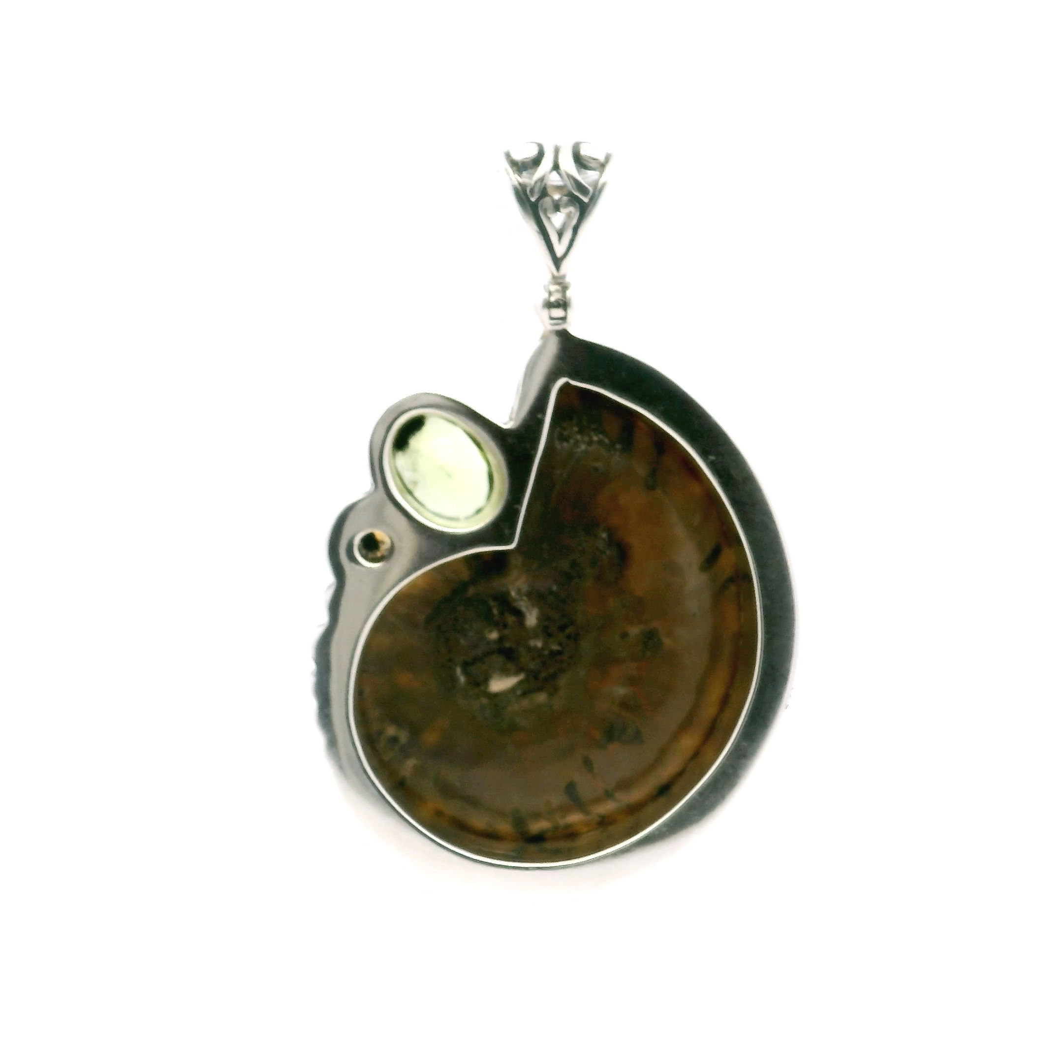 Discover the enchanting beauty of our Ammonite Fossil Pendant. Featuring an open ammonite cross-section inlaid with vibrant smithsonite and accented by a faceted peridot and citrine, this pendant blends ancient history with brilliant color. Crafted in 925 sterling silver with intricate bead and line detailing, it’s a striking symbol of nature’s artistry and expert craftsmanship. Perfect for those who value rare, meaningful jewelry, this piece brings timeless elegance to any collection. Ammonite Fossil Pendant - Open Ammonite Cross-section Inlaid with Smithsonite with Faceted Peridot Oval & Citrine Round Bezel Set in 925 Sterling Silver with Bead & Line Accents