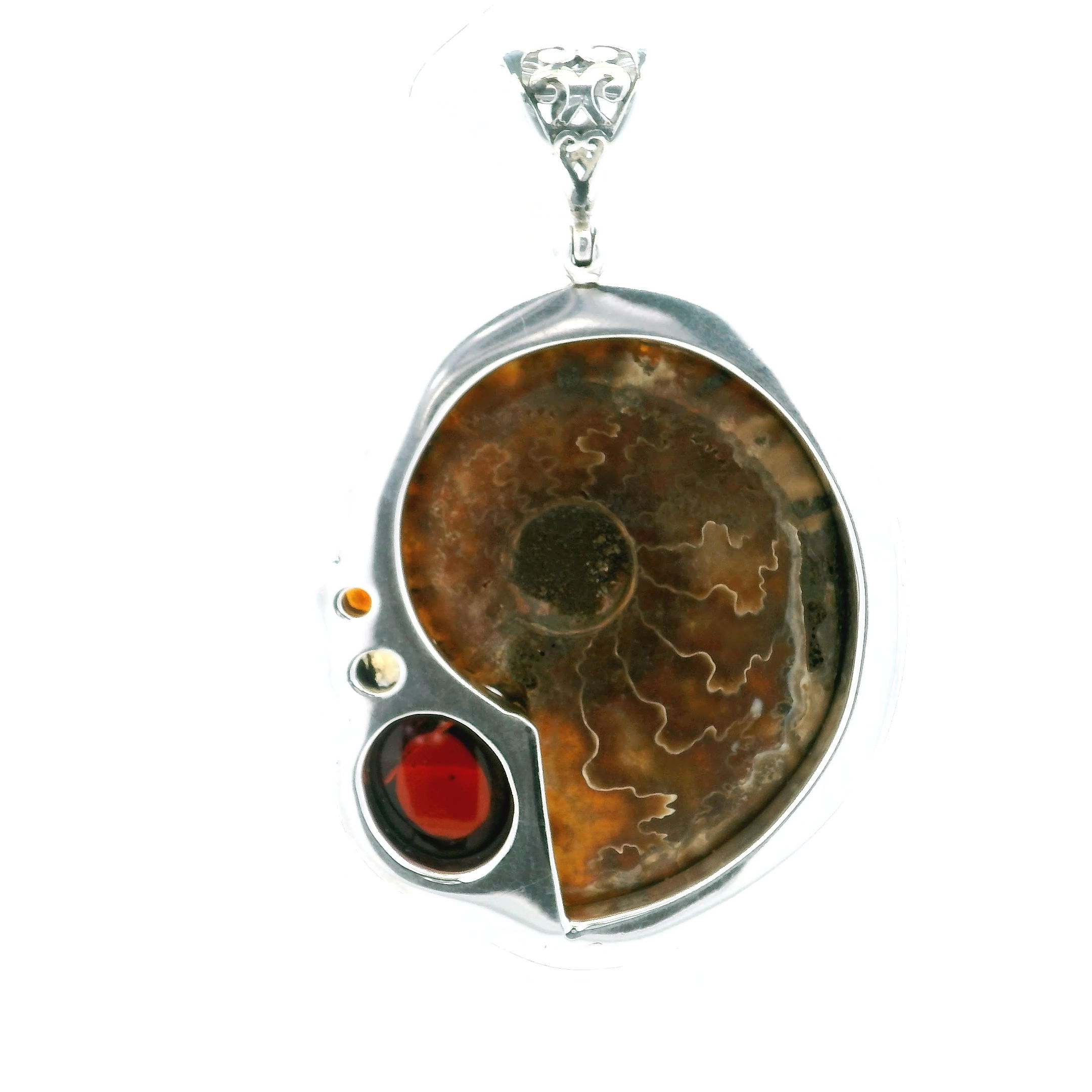 Discover the captivating beauty of our Ammonite Fossil Pendant, a stunning piece that unites natural history with refined craftsmanship. Featuring an inverted cross-section of a genuine ammonite fossil, this pendant showcases the fossil’s timeless spiral, masterfully inlaid with shimmering rutilated quartz to highlight every intricate detail.At its heart lies a deep, oval garnet cabochon—rich in color and luminous with every turn. Accented by bezel-set faceted garnet and citrine rounds, the pendant radiates warm red and golden tones that contrast beautifully against the cool brilliance of 925 sterling silver.The result is a bold yet harmonious composition that honors the fossil’s ancient origins while embracing a modern, sophisticated aesthetic.Crafted for women who appreciate the beauty of natural wonders and the uniqueness of artisan design, this pendant is more than jewelry—it’s a statement of individuality and a tribute to the Earth’s enduring artistry. Whether worn daily or saved for special occasions, it adds depth, elegance, and unmistakable character to any look.Wear a piece of the planet’s story with grace—where the past inspires the present in one unforgettable design. Ammonite Fossil Pendant - Open Inverted Ammonite Cross-section Inlaid with Rutilated Quartz with Oval Garnet Cabochon & Faceted Garnet & Citrine Rounds Bezel Set in 925 Sterling Silver