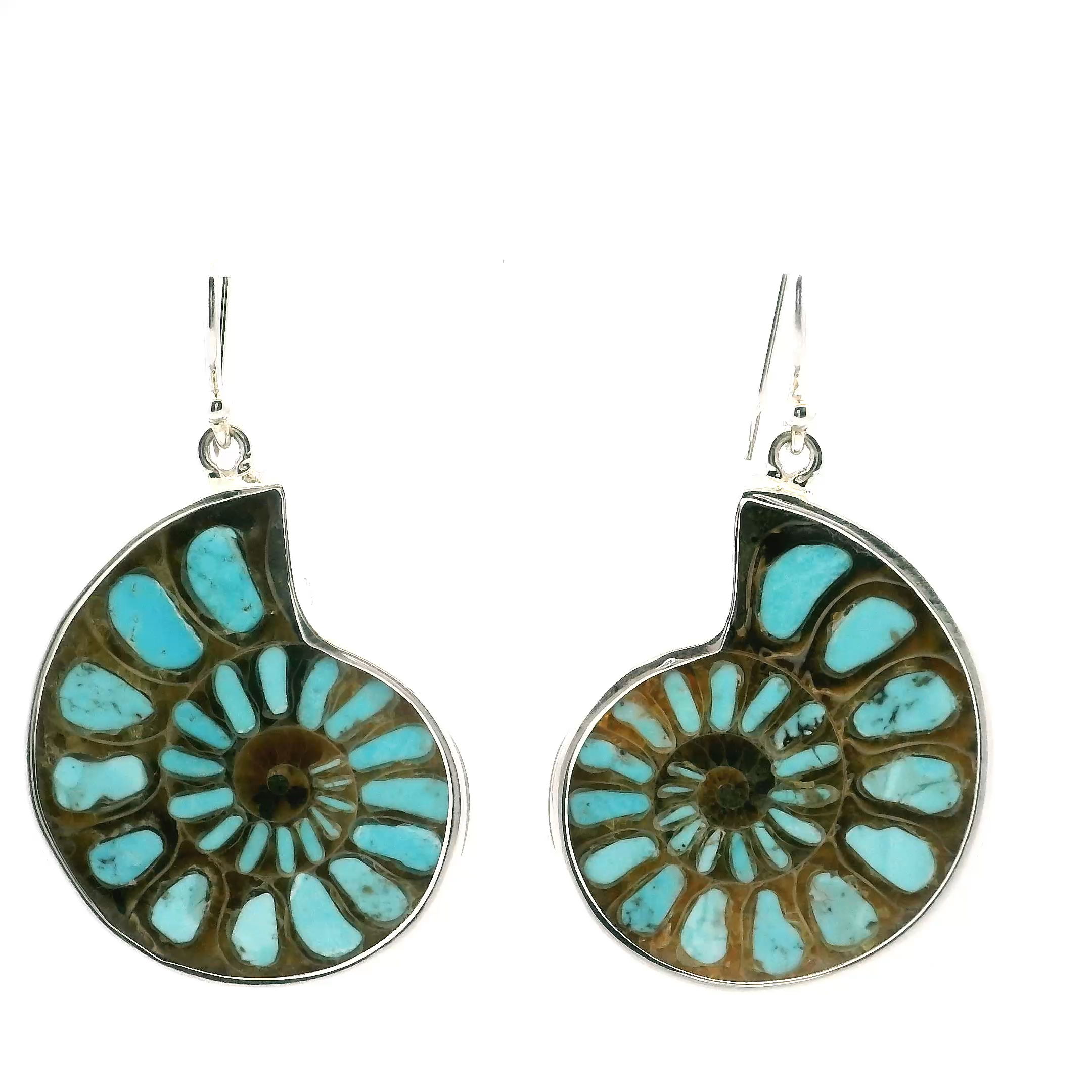 Make a bold yet graceful statement with our Ammonite Fossil & Turquoise Dangle Earrings, where ancient history meets vibrant modern style. Each earring features a beautifully preserved ammonite fossil, its swirling chambers offering a natural glimpse into life from millions of years ago.Paired with a vivid turquoise accent, these earrings bring together earthy textures and bright, calming color. The contrast between the fossil’s organic patterns and the turquoise’s brilliant hue creates a truly eye-catching design. Expertly crafted from premium materials, the earrings are finished with secure, comfortable dangle hooks that make them easy to wear all day long.Perfect for both special occasions and everyday wear, these earrings offer versatility and meaning in every detail. Choosing fossil and gemstone jewelry is also a celebration of sustainable style—each piece honors the planet’s beauty while treading lightly on it.Whether gifting or indulging yourself, the Ammonite Fossil & Turquoise Earrings are more than accessories—they’re wearable stories of earth, ocean, and timeless elegance. Ammonite Fossil Dangle Earrings - Cross-section Inlaid with Robins Egg Blue Arizona Turquoise Bezel Set in 925 Sterling Silver