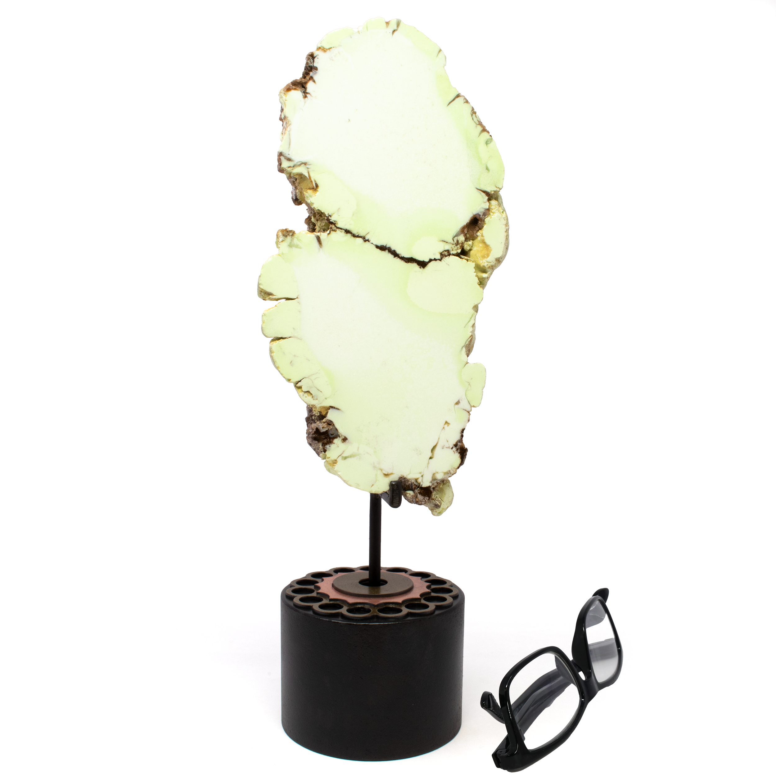 Add a touch of elegance and natural beauty to your home decor with our Pastel Green Chrysoprase End Cut on a Rotating Custom Stand. Sourced from the lush terrains of Australia, this exquisite piece showcases the unique allure of chrysoprase, famed for its vibrant green hue and eye-catching veining. The intricate patterns elegantly slice through the center, creating a mesmerizing focal point that draws the eye and sparks conversation.Expertly mounted on a rotating custom stand, this tabletop accessory allows you to appreciate the stone's natural beauty from every angle. The dynamic display offers versatility, effortlessly complementing a range of decor styles from contemporary to classic, making it a perfect addition to any room in your home. Pastel Green Chrysoprase End Cut on Rotating Custom Stand from Australia with Veining Through Center aka Citron Magnesite