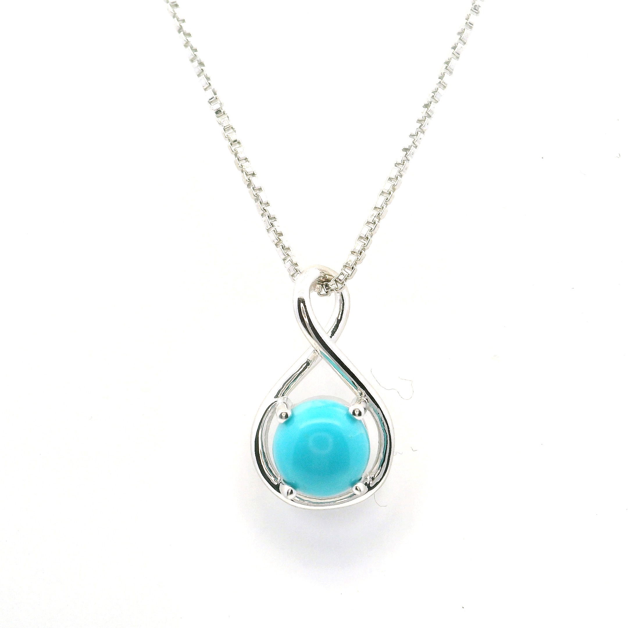 This New Mexican Turquoise Necklace features a dainty round cabochon of genuine turquoise, prong-set within a North/South Infinity-inspired frame crafted in 925 sterling silver. The soft blue hue of the stone contrasts beautifully with the polished silver setting, symbolizing enduring elegance and natural harmony.Suspended from a fine sterling silver chain, the pendant rests delicately at the collarbone, offering versatility for both everyday wear and special occasions. A quiet fusion of modern sophistication and Southwestern tradition, this necklace is a timeless piece that brings grace and individuality to any collection. New Mexican Turquoise Necklace- Dainty Round Cabochon Prong Set in North/South Infinity in 925 Sterling Silver with Chain