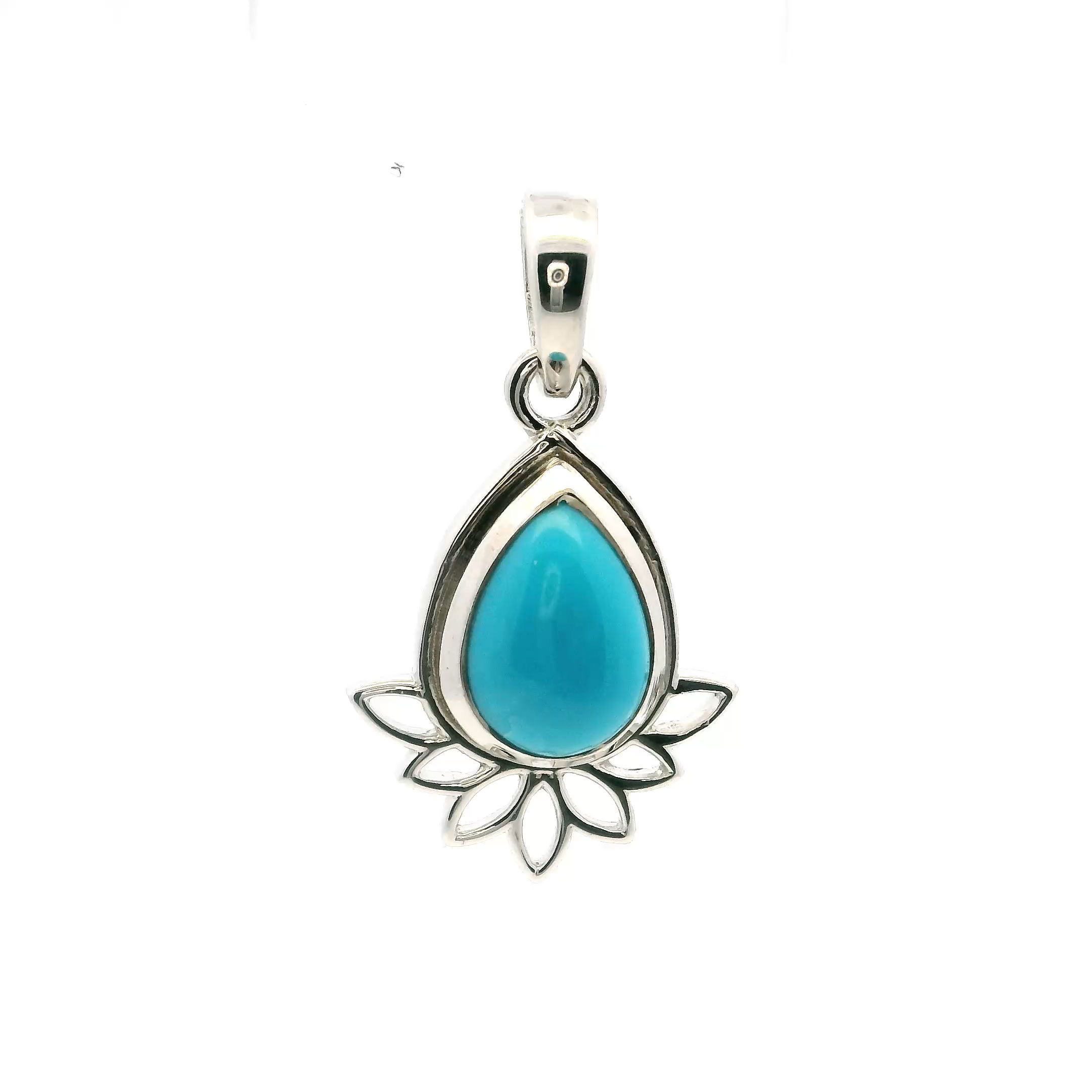 This New Mexican Turquoise Pendant features a striking teardrop cabochon, its blue-green surface alive with intricate matrix patterns that speak to the stone’s raw, untamed origin. Bezel set in 925 sterling silver, the turquoise rests within a refined frame that enhances its depth and vibrancy. Above the stone, a delicate lotus motif adds quiet symbolism—purity, renewal, and spiritual grace—lending deeper resonance to this already captivating design.Graceful yet grounded, this pendant offers a meaningful blend of elegance and intention. Ideal for women who gravitate toward pieces with soul and story, it brings a touch of Southwestern heritage and personal symbolism to any ensemble. A timeless keepsake that transcends trends, inviting beauty and serenity into everyday life. New Mexican Turquoise Pendant - Teardrop Cabochon with Lotus Design Bezel Set in Simple 925 Sterling Silver