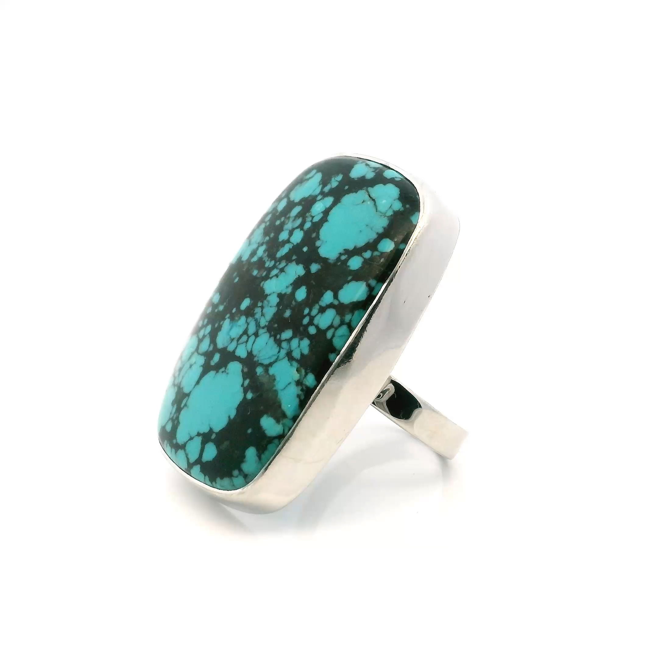 This Tibetan Turquoise Ring features a rounded rectangle cabochon rich with vivid blue-green color and dramatic black inclusions, each stone naturally unique and full of character. Bezel set in simple 925 sterling silver, the clean lines of the setting allow the stone’s organic beauty to shine, making it an elegant and versatile addition to any jewelry collection.The band is adjustable by 1.5+ sizes, offering both comfort and flexibility for everyday wear. Whether worn solo as a striking focal point or layered with other pieces, this ring brings a grounded, artisan feel to any ensemble—perfect for those who value the timeless appeal of natural stones and handcrafted design. Tibetan Turquoise Ring - Rounded Rectangle Cabochon with Black Inclusions Bezel Set in Simple 925 Sterling Silver szAdj 1.5"+