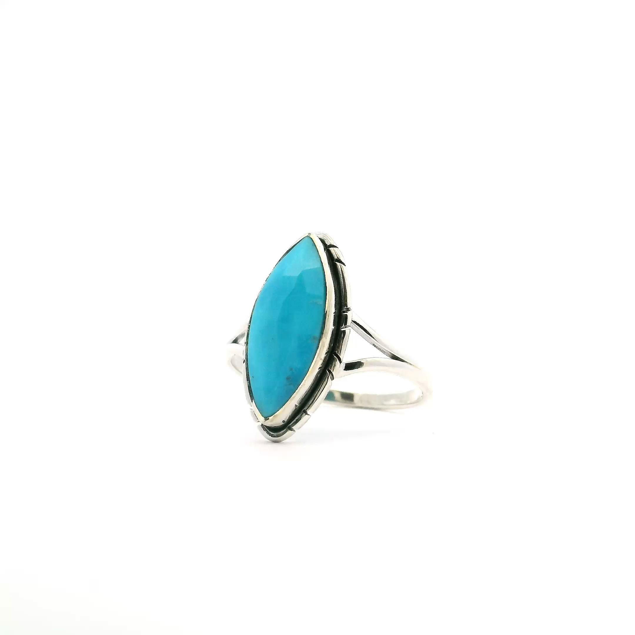 This size 9 ring features a sharp oval faceted turquoise stone from New Mexico, bezel set in polished 925 sterling silver. Stamped line detailing around the setting adds artisanal charm, while the elegant double band offers comfort and support.Bold, vibrant, and timeless, this ring is a perfect fusion of Southwestern heritage and refined design—ideal for everyday wear or as a standout statement piece. New Mexican Turquoise Ring - Faceted Sharp Oval Bezel Set with Stamped Line Detail & Double Band in 925 Sterling Silver sz9