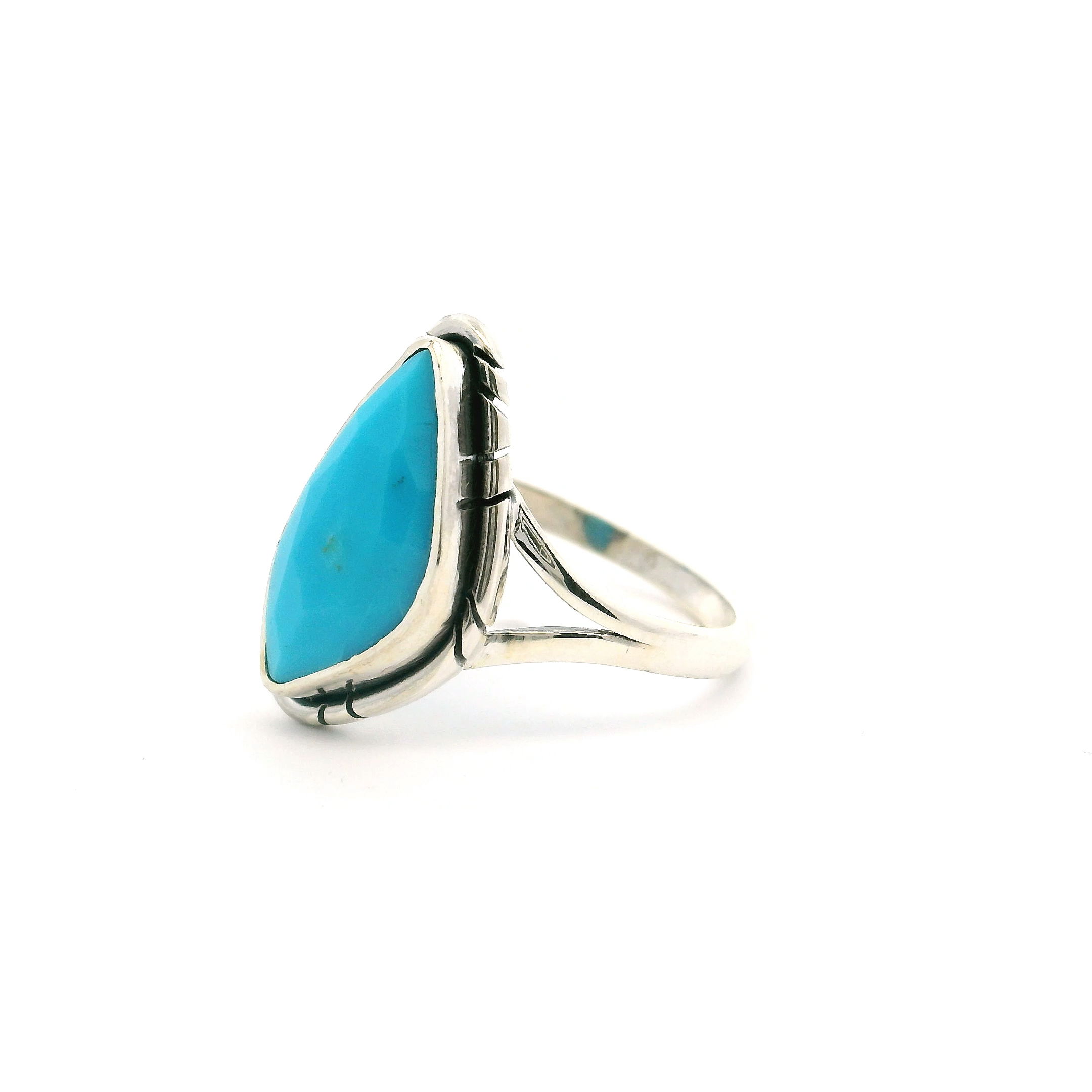 This elegant size 5 ring features a faceted turquoise stone in a unique sideways triangle cut, bezel set in 925 sterling silver. Surrounded by delicate stamped line detailing, it blends modern design with traditional Southwestern charm.A double band adds structure and sophistication, making this ring a standout piece for daily wear or special occasions—perfect for those who value bold, handcrafted style with cultural roots. New Mexican Turquoise Ring - Faceted Sideways Triangle Bezel Set With Stamped Line Detail & Double Band In 925 Sterling Silver sz5