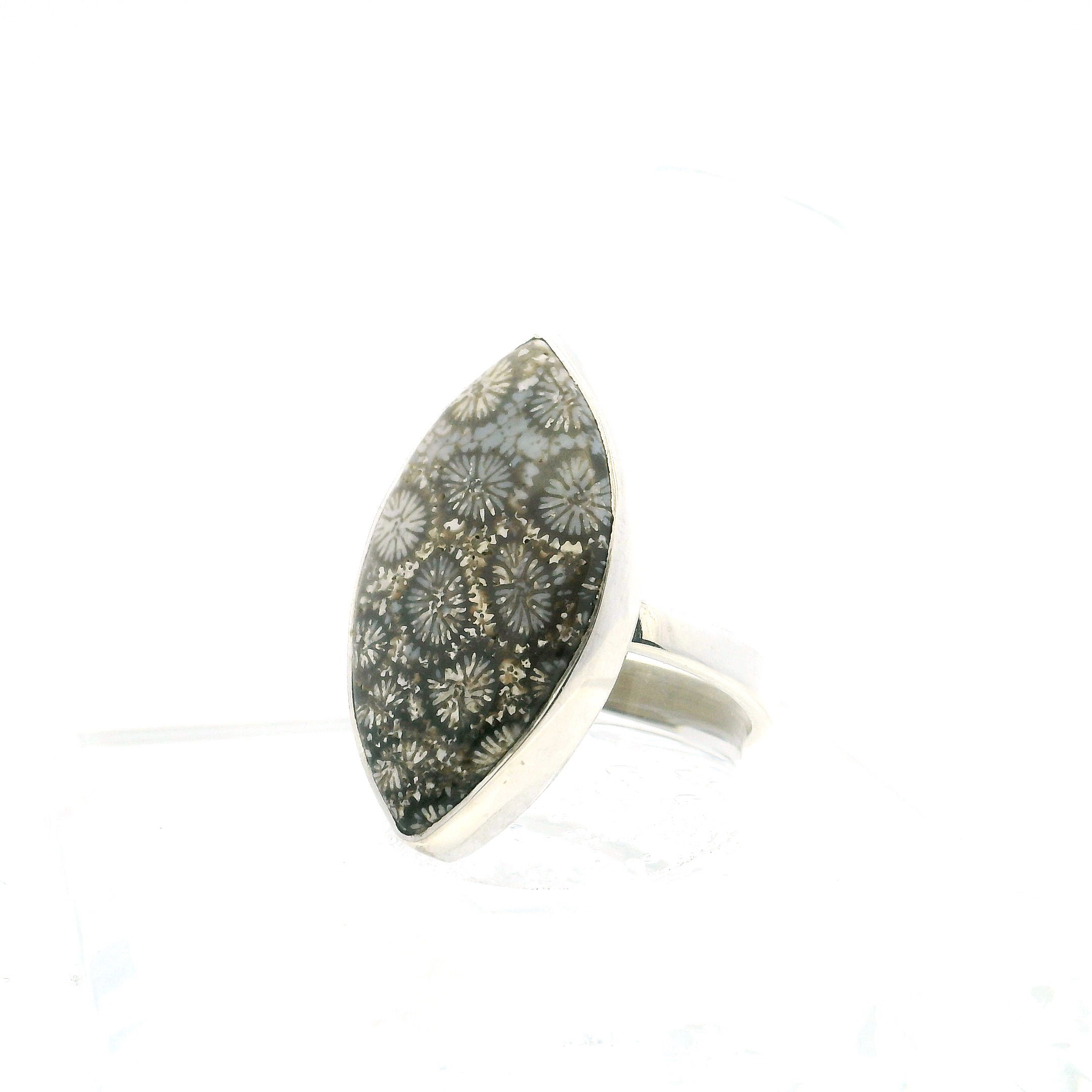 Fossilized Coral Ring – a striking union of ancient natural beauty and modern minimalism. Featuring a sharp oval cabochon of fossilized coral, this size 9 ring is bezel set in simple 925 sterling silver, allowing the stone’s intricate floral patterns and earthy hues to take center stage. Each detail within the coral tells a story formed over millions of years, offering a quiet, organic elegance.The clean silver setting complements the fossil’s rich texture without distraction, creating a piece that is both timeless and contemporary. Durable, refined, and effortlessly wearable, this ring is perfect for nature lovers and admirers of one-of-a-kind gemstone jewelry. Fossilized Coral Ring - Sharp Oval Cabochon Bezel Set in Simple 925 Sterling Silver sz9