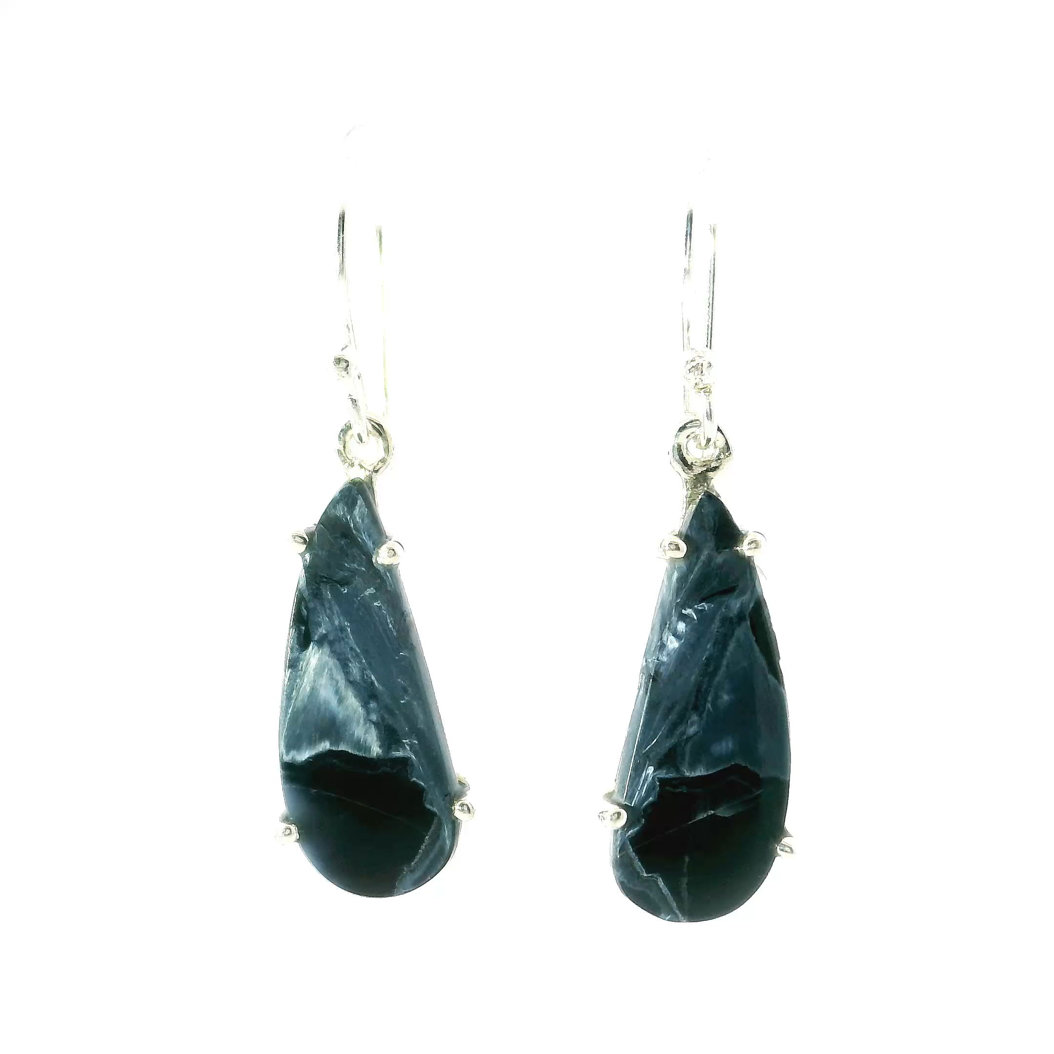 These stunning earrings feature teardrop-shaped Pietersite cabochons, prong set in polished 925 sterling silver. Each stone reveals dynamic, swirling patterns of deep blue, gold, and earthy tones—capturing the stormy beauty Pietersite is known for.Lightweight with graceful movement, they’re perfect for everyday wear or special occasions. A timeless blend of nature’s artistry and refined craftsmanship, ideal for anyone who loves bold, elegant jewelry. Pietersite Dangle Earrings - Teardrop Cabochon Prong Set in 925 Sterling Silver