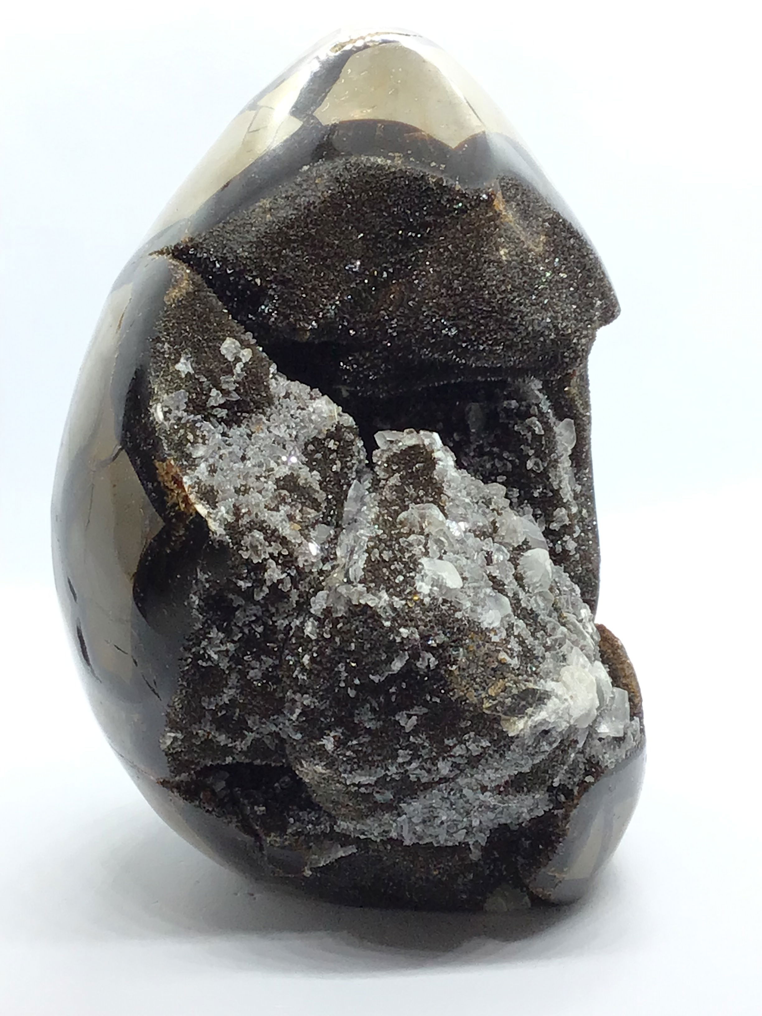 Crafted from Madagascar's ancient terrain, this Septarian Druze Geode Egg showcases bold geometric patterns and sparkling calcite inclusions that reveal Earth’s rich geological story. Each piece is one-of-a-kind, featuring a cut base for stable, elegant display.With its earthy tones and organic form, this egg adds grounding energy and timeless beauty to any collection or space. A thoughtful gift or personal keepsake, it brings the raw magic of nature into your everyday environment. Septarian Druze Geode Freeform Egg with Cut Base from Madagascar - Calcite Crystal Inclusions