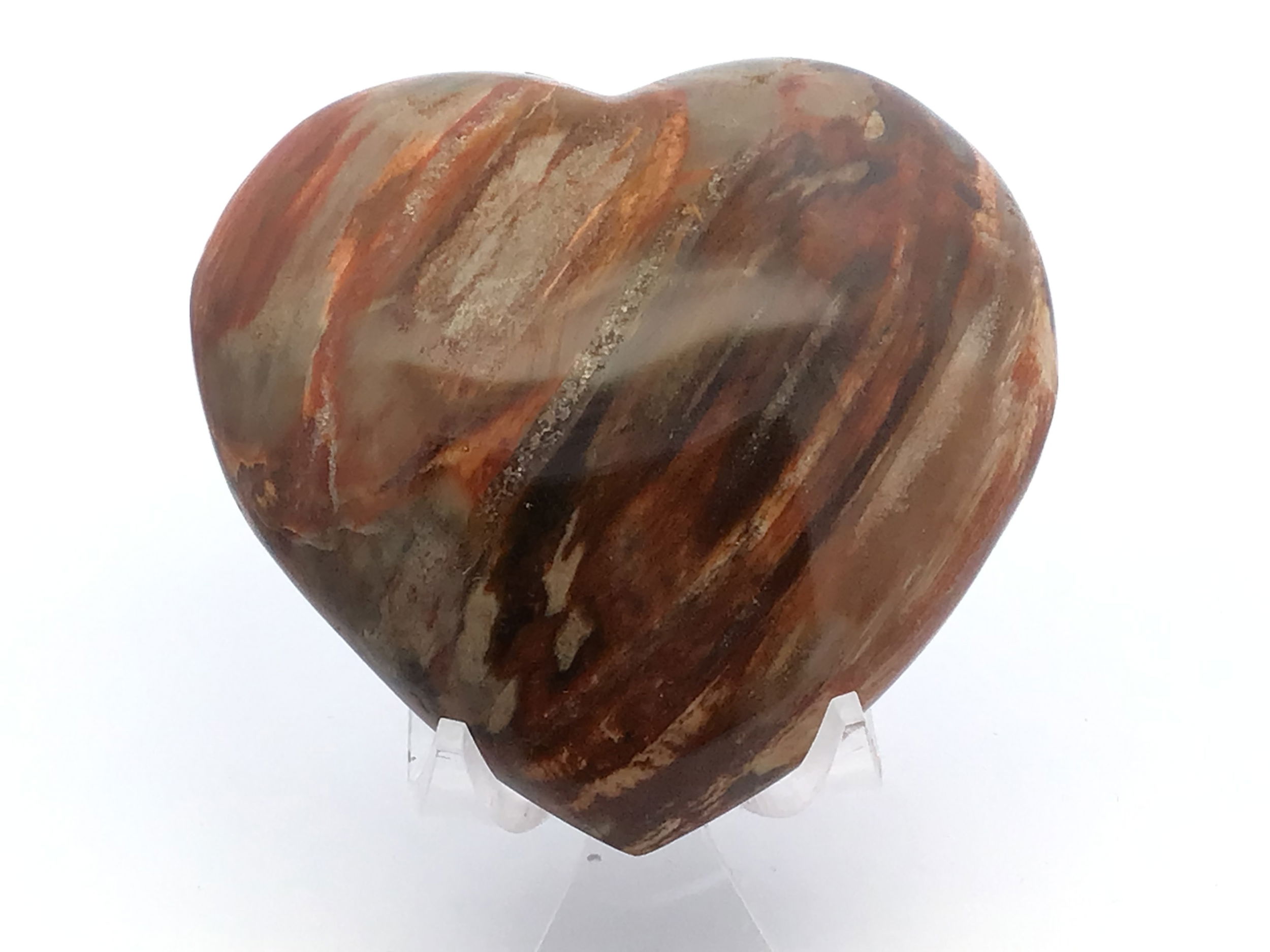 This heart-shaped petrified wood specimen from Madagascar showcases rich, earthy tones and organic patterns formed over millions of years. Expertly carved and polished, it’s a symbol of love and resilience—making it both meaningful and visually stunning.Displayed on a clear Lucite stand for a clean, modern touch, it’s ideal for collectors, nature lovers, or anyone seeking a unique blend of ancient beauty and contemporary design. A timeless addition to any space. Madagascar Petrified Wood Heart with Lucite Stand