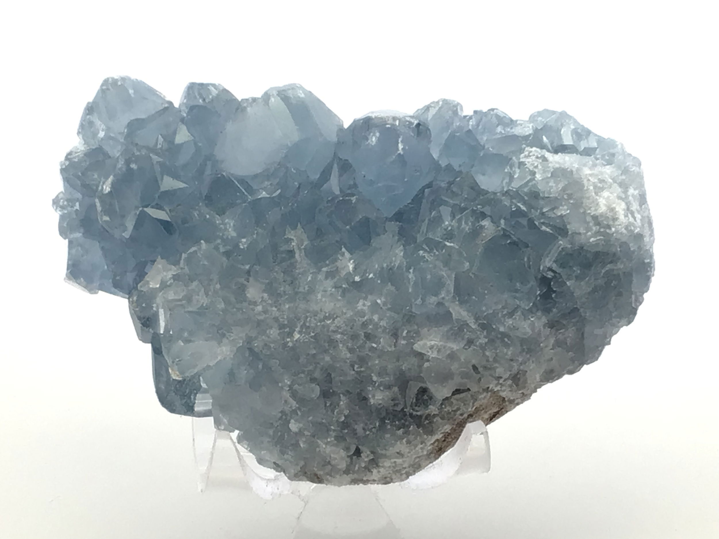 Known for its serene blue hues and delicate crystal formations, this remarkable specimen captures the essence of celestial wonder, offering a tranquil energy to any space it graces.Expertly sourced from the rich mineral deposits of Madagascar, each Celestine specimen is naturally unique, displaying its own distinct crystal structure and shades of blue, reminiscent of a clear sky infused with peace and harmony.Accompanied by a clear, sleek Lucite stand, this Celestine specimen is elegantly showcased, elevating its aesthetic appeal. The stand not only enhances the crystal's natural beauty but also provides stability and a modern touch to complement any decor.Celestine is renowned for its calming and uplifting properties, often used to promote clarity of mind and enhance communication. This crystal can be a powerful ally for meditation, encouraging a sense of tranquility and spiritual awareness. Celestine Crystal Specimen from Madagascar with Lucite Stand
