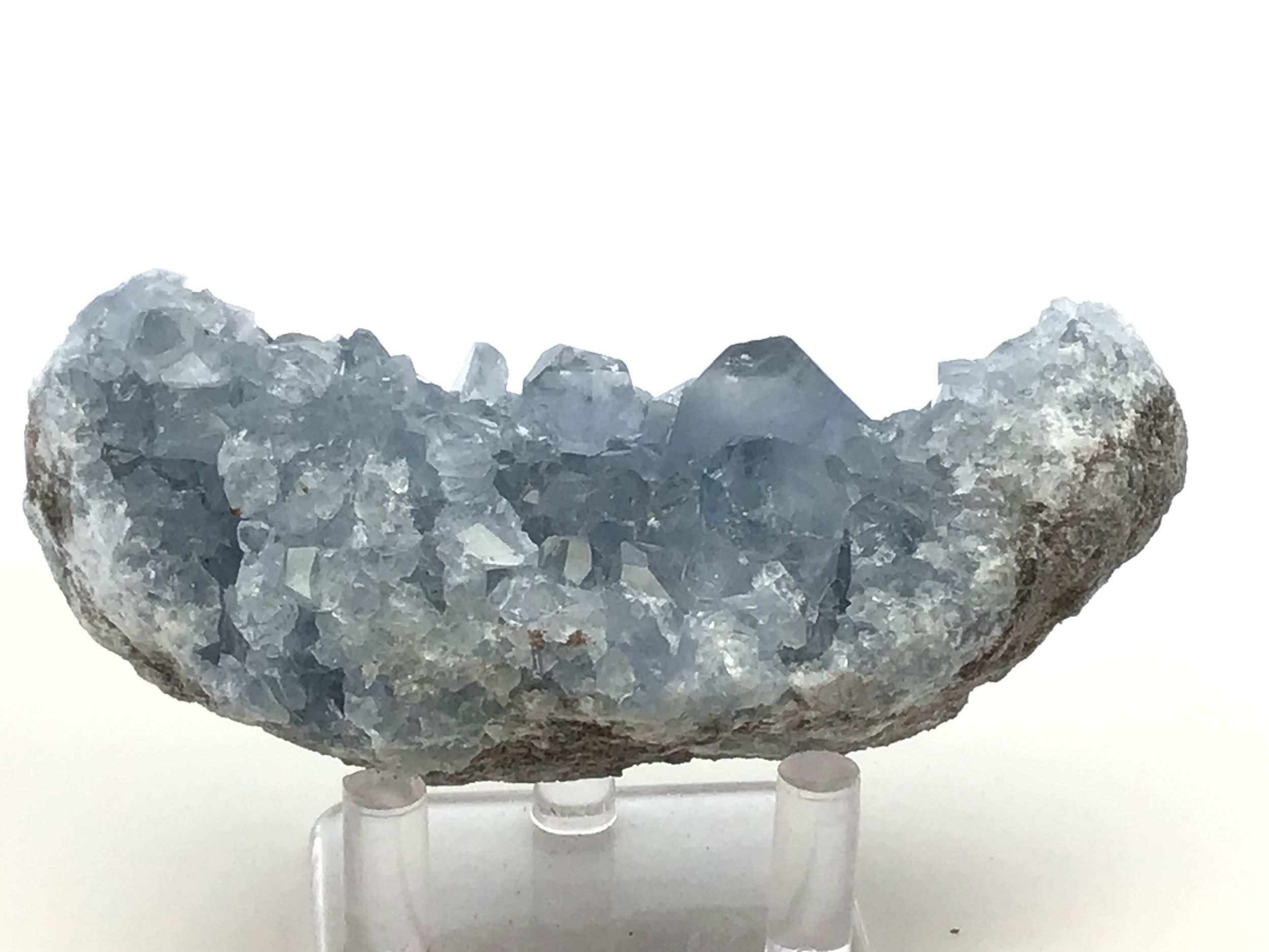 Known for its serene blue hues and delicate crystal formations, this remarkable specimen captures the essence of celestial wonder, offering a tranquil energy to any space it graces.Expertly sourced from the rich mineral deposits of Madagascar, each Celestine specimen is naturally unique, displaying its own distinct crystal structure and shades of blue, reminiscent of a clear sky infused with peace and harmony.Accompanied by a clear, sleek Lucite stand, this Celestine specimen is elegantly showcased, elevating its aesthetic appeal. The stand not only enhances the crystal's natural beauty but also provides stability and a modern touch to complement any decor.Celestine is renowned for its calming and uplifting properties, often used to promote clarity of mind and enhance communication. This crystal can be a powerful ally for meditation, encouraging a sense of tranquility and spiritual awareness. Celestine Crystal Specimen from Madagascar with Lucite Stand