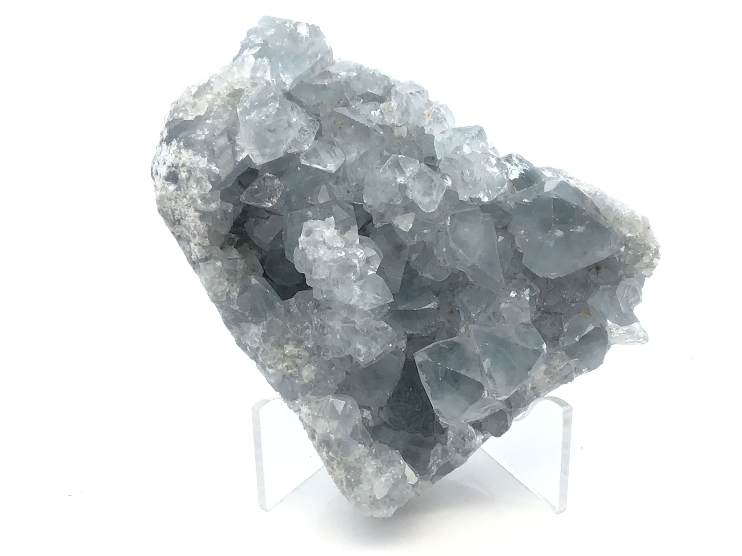Celestine Crystal Specimen from Madagascar with Lucite Stand, a serene expression of nature’s quiet majesty, features delicate sky-blue crystals nestled in their raw matrix and elegantly elevated on a minimalist lucite base. Sourced from the mineral-rich regions of Madagascar, this specimen reveals clustered celestine formations that shimmer with an otherworldly translucence, invoking calm and connection to higher realms.The cool, tranquil color palette evokes stillness, while the refined lucite display highlights the stone’s natural geometry, offering a sense of levity and grace. Ideal for collectors or interior spaces seeking a moment of peace, this specimen is both a geological marvel and a contemplative work of art. Celestine Crystal Specimen from Madagascar with Lucite Stand
