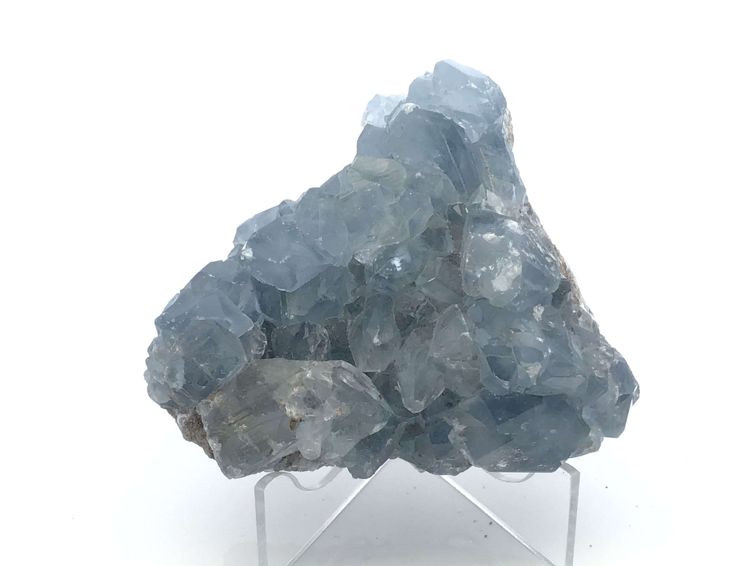Celestine Crystal Specimen from Madagascar with Lucite Stand, a serene expression of nature’s quiet majesty, features delicate sky-blue crystals nestled in their raw matrix and elegantly elevated on a minimalist lucite base. Sourced from the mineral-rich regions of Madagascar, this specimen reveals clustered celestine formations that shimmer with an otherworldly translucence, invoking calm and connection to higher realms.The cool, tranquil color palette evokes stillness, while the refined lucite display highlights the stone’s natural geometry, offering a sense of levity and grace. Ideal for collectors or interior spaces seeking a moment of peace, this specimen is both a geological marvel and a contemplative work of art. Celestine Crystal Specimen from Madagascar with Lucite Stand