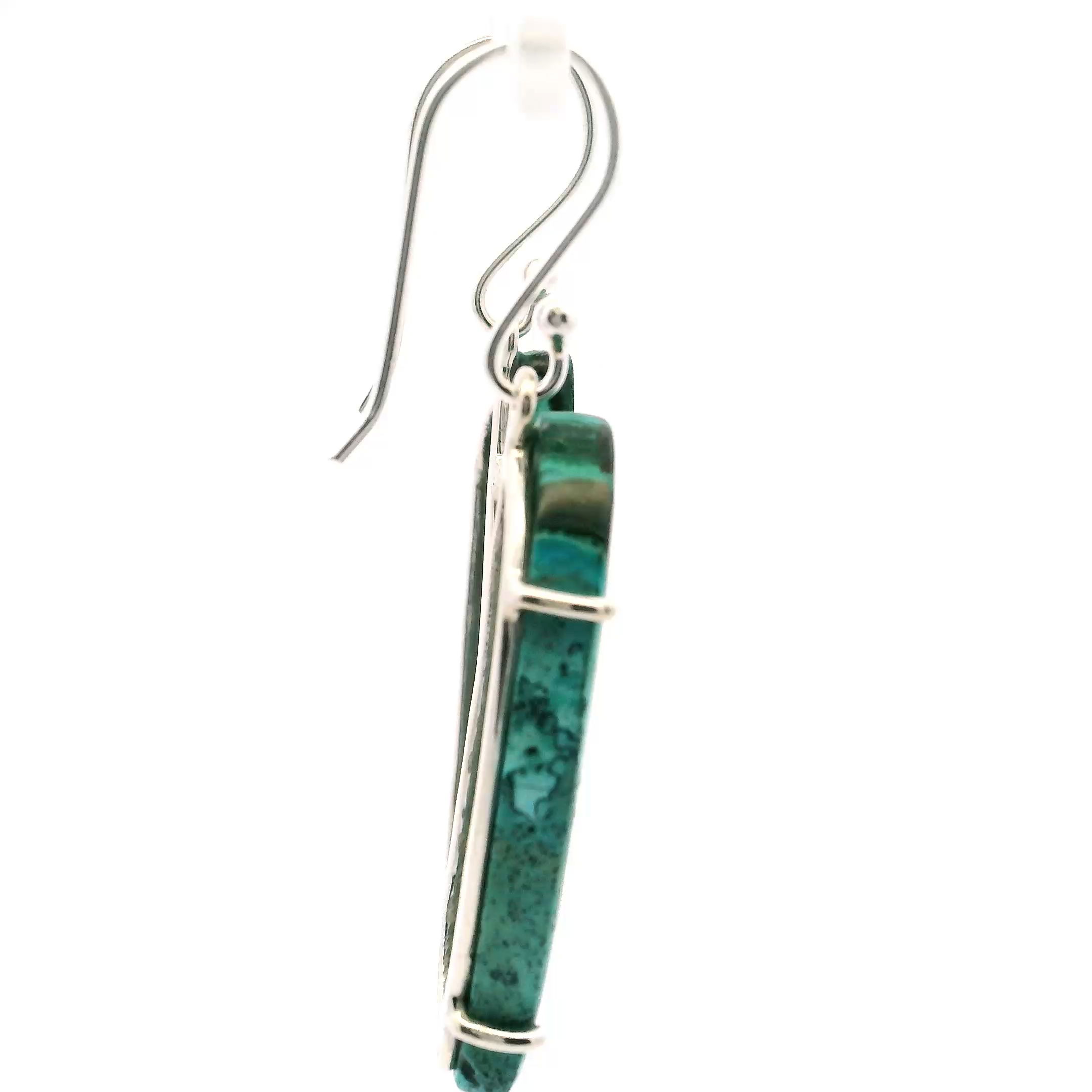 Elevate your jewelry collection with the Chrysocolla Malachite Dangle Earrings, featuring elongated S-shaped cabochons that showcase a flowing mix of light green, deep forest tones, and aqua blue. The natural banding of chrysocolla malachite evokes serene landscapes, offering a vibrant yet grounded look.Prong-set in polished 925 sterling silver, each stone is securely framed to highlight its color and movement. Lightweight and graceful, these earrings sway elegantly, adding an artful touch to both everyday outfits and special occasions. Chrysocolla Malachite Dangle Earrings - Long S-Shaped Cabochon with Straight Vertical Bands of LIght Green & Dark Green & Aqua Prong Set in 925 Sterling Silver