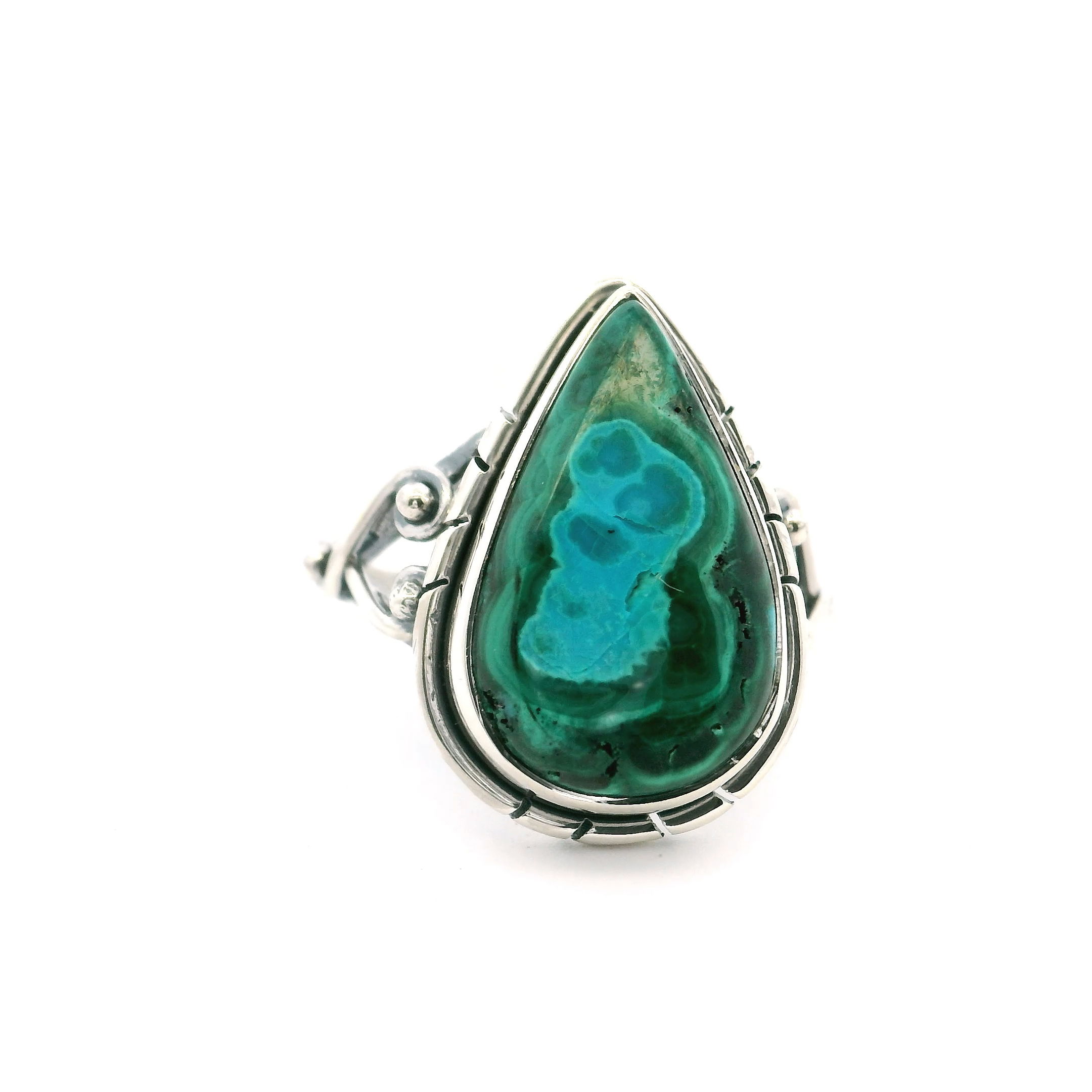 Add a touch of natural elegance to your collection with this Chrysocolla Malachite Ring, featuring a vibrant aqua blue teardrop cabochon set in 925 sterling silver. The stone’s swirling, ghostly patterns create a one-of-a-kind visual, making each ring a unique expression of Earth’s artistry.Sized at 5 and designed with a double wishbone band, this piece blends classic craftsmanship with a modern twist. Comfortable and striking, it’s perfect for everyday wear or special occasions—an ideal choice for anyone drawn to nature’s beauty and timeless style. Chrysocolla Malachite Ring - Teardrop Cabochon With Aqua Blue Ghost And Double Band With Wishbone On Sides Bezel Set In 925 Sterling Silver sz5