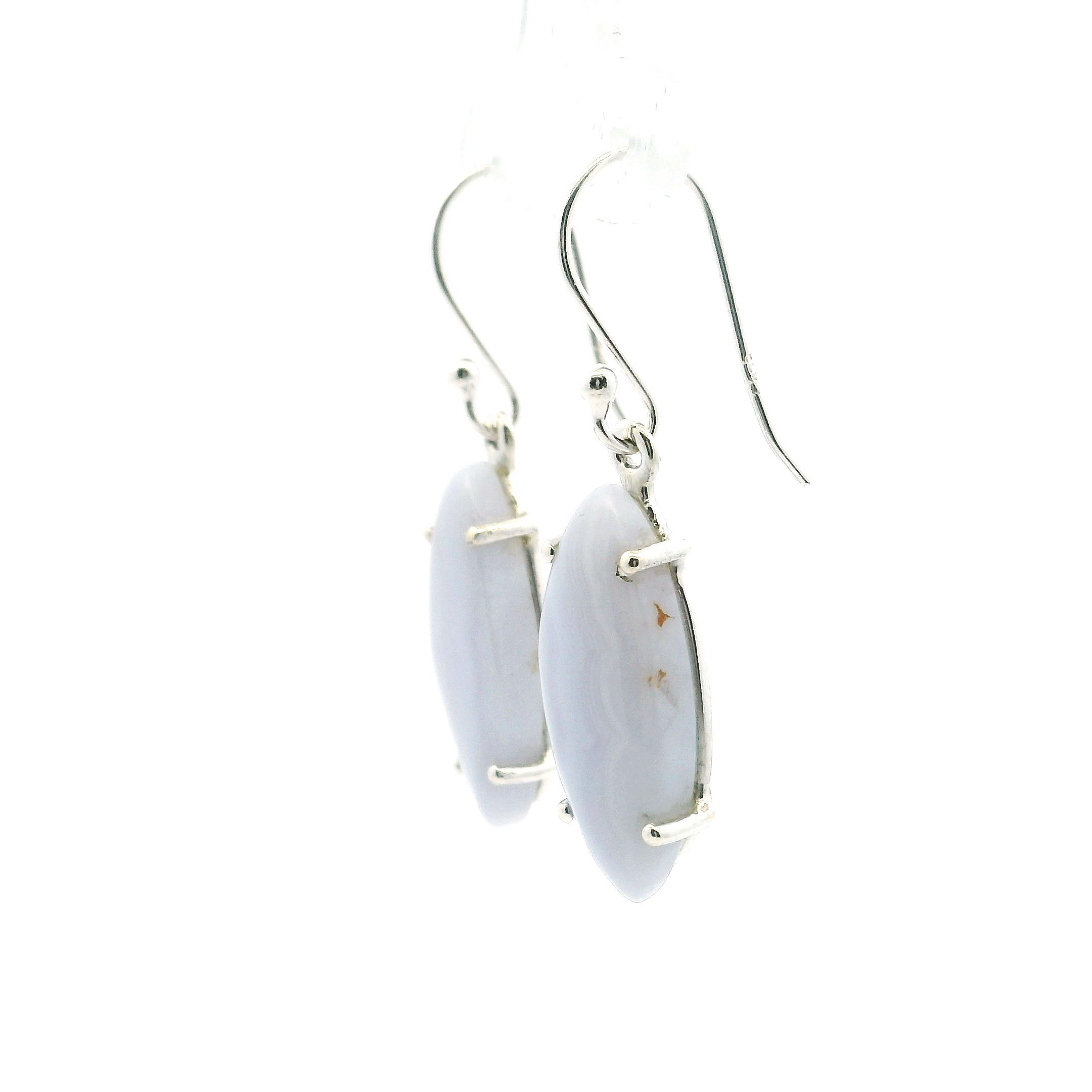 Indulge in the serene elegance of our Blue Lace Agate Dangle Earrings, featuring sharp oval cabochons prong-set in polished 925 sterling silver. Each genuine Blue Lace Agate stone displays soft sky-blue tones laced with intricate white banding, offering a tranquil, ethereal beauty unique to every pair.Lightweight and refined, these earrings combine comfort with sophisticated charm, making them ideal for both everyday wear and special occasions. A graceful expression of nature’s artistry, they bring a touch of calm and timeless style to any jewelry collection. Blue Lace Agate Dangle Earrings - Sharp Oval Cabochon with Full Vertical Banding Prong Set in 925 Sterling Silver