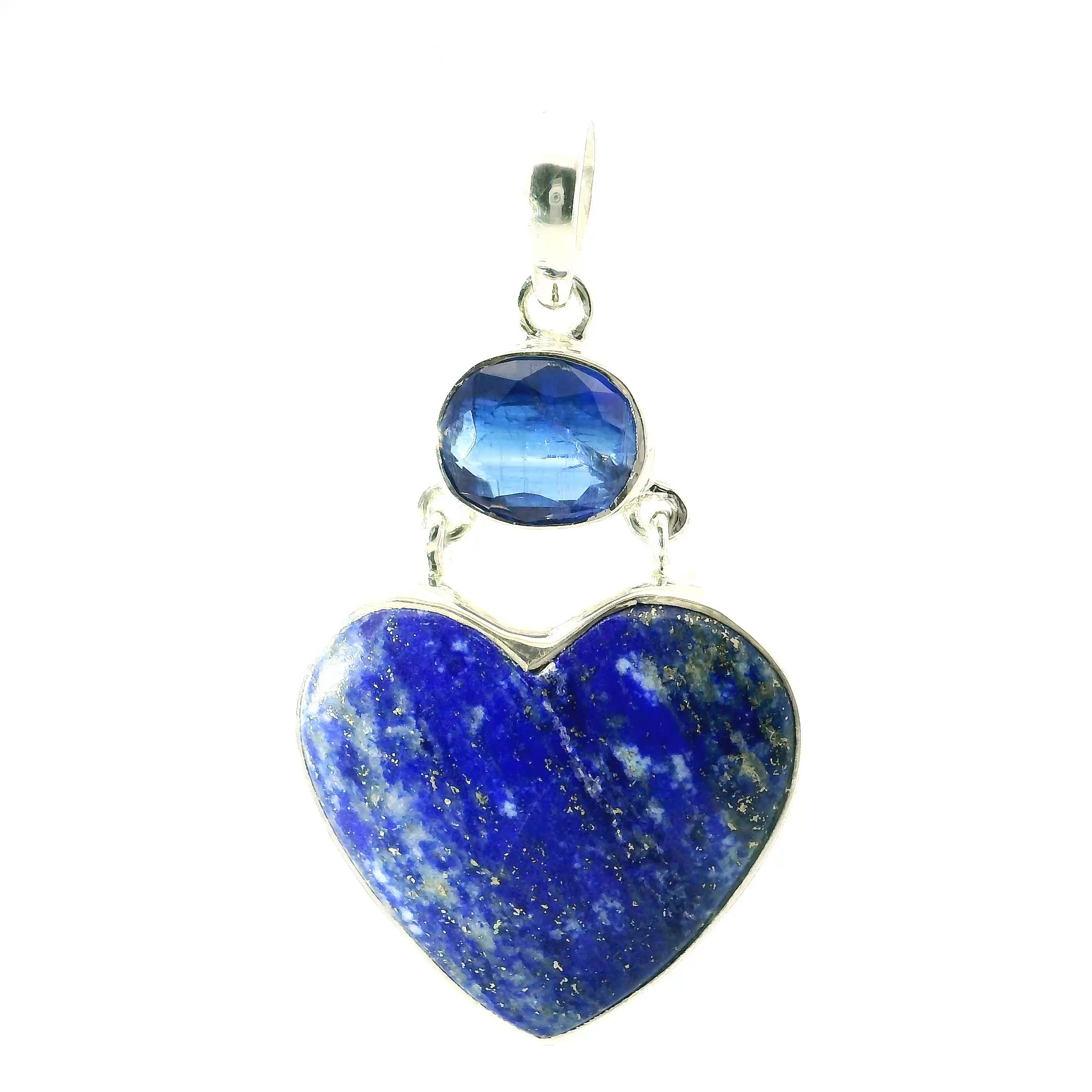 Lapis Lazuli Pendant with Heart Cabochon and East-West Faceted Kyanite in 925 Sterling Silver — This captivating pendant showcases a heart-shaped cabochon of lapis lazuli, rich in deep blue hues and naturally dusted with golden pyrite. Above it, a faceted oval kyanite is bezel set horizontally, creating a sleek east-west alignment that adds modern elegance to the design. The pairing of lapis and kyanite offers a striking contrast—bold and grounding below, cool and luminous above.Both gemstones are bezel set in 925 sterling silver, chosen for its lasting brilliance and strength. The clean silver frame enhances the richness of the stones while offering a refined silhouette. This piece blends artisan craftsmanship with the raw beauty of natural gems, making it an ideal pendant for women who appreciate meaningful, distinctive jewelry that transitions effortlessly from day to evening. Lapis Lazuli Pendant - Heart Cabochon below Faceted East-West Kyanite Oval Bezel Set in 925 Sterling Silver