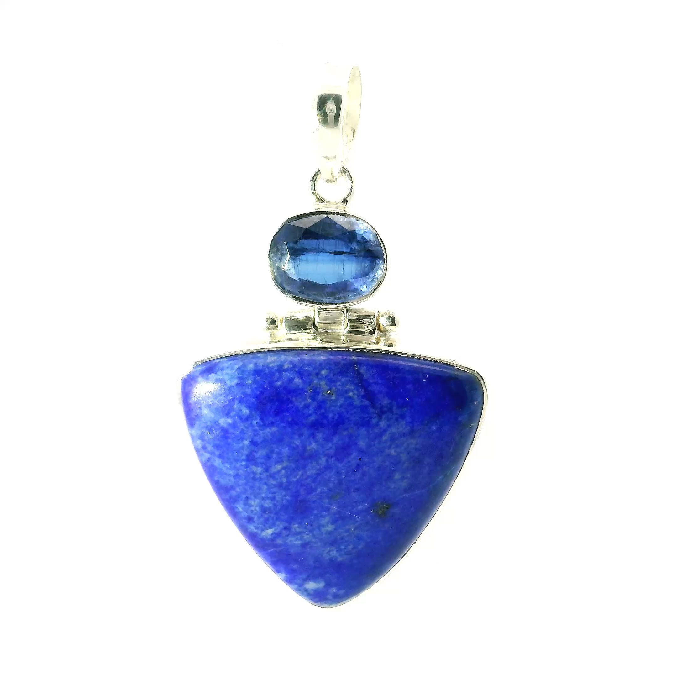 Lapis Lazuli and Kyanite Pendant in Sterling Silver, featuring a dramatic triangular lapis cabochon paired with a faceted east-west oval kyanite. The deep, celestial blue of the lapis—flecked with golden pyrite—evokes the night sky, while the shimmering kyanite above adds a touch of silken luminosity. Both stones are bezel set in high-quality 925 sterling silver, offering a sleek and modern finish with lasting durability.This pendant’s bold geometry and rich color contrast make it a standout piece, perfect for layering or wearing solo as a statement. A refined blend of bohemian spirit and timeless elegance, ideal for collectors of unique gemstone jewelry or those drawn to the grounding and ethereal energy of natural stones. Lapis Lazuli Pendant - Triangular Cabochon Below Faceted East-West Kyanite Oval Bezel Set in 925 Sterling Silver