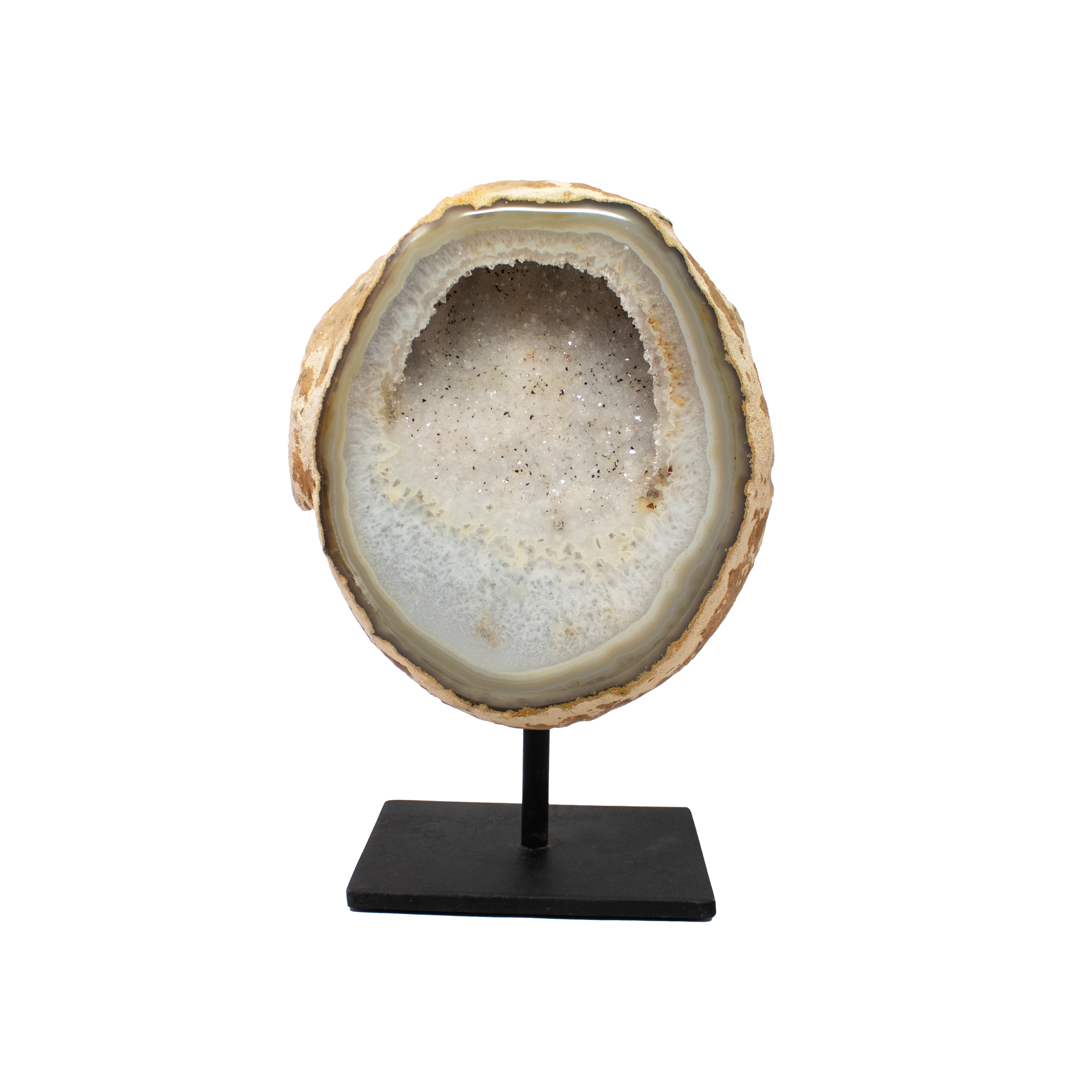 The Agate Druze Geode on Post Stand features a shallow crystalline pocket dusted in soft pink hues, offering a serene, luminous glow that adds warmth and refinement to any setting. Sourced from Brazil, this one-of-a-kind geode is mounted on a minimalist post stand, balancing organic beauty with contemporary design. Subtle banding and delicate druze sparkle beneath the surface, drawing the eye and soothing the senses.Agate is cherished for its calming, grounding properties, and this piece serves as both a striking decorative accent and a gentle energetic anchor. Ideal for shelves, desks, or sacred spaces, it invites quiet reflection while elevating your decor with understated elegance. Agate Druze Geode on Post Stand from Brazil with Shallow Pocket of Soft Pink Hue Druze