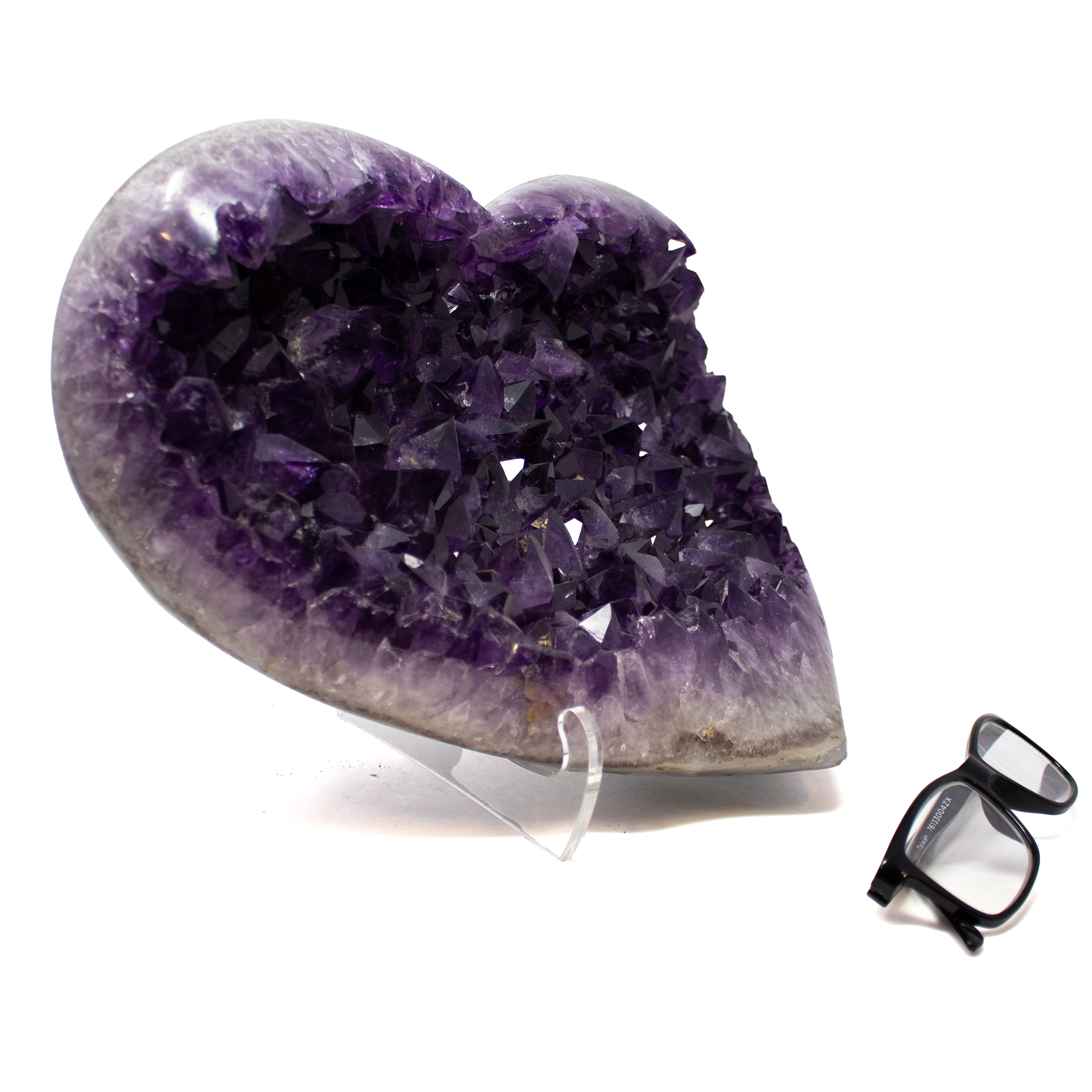 The Amethyst Crystal Heart from Brazil is a striking fusion of natural elegance and modern form, hand-carved into a perfectly symmetrical heart and set on a minimalist Lucite stand. Radiating rich violet hues, the crystal captures light and energy, revealing the inner depths of this cherished stone known for its calming, protective properties.Sourced from Brazil’s renowned amethyst deposits, this piece is a symbol of love and spiritual wisdom, sculpted to perfection and elevated by the geometric clarity of its transparent base. Whether displayed as a centerpiece or gifted as a meaningful token, it offers a serene presence and refined beauty—ideal for collectors, healers, and design-conscious admirers of nature’s finest minerals. Amethyst Crystal Heart from Brazil on Lucite Stand