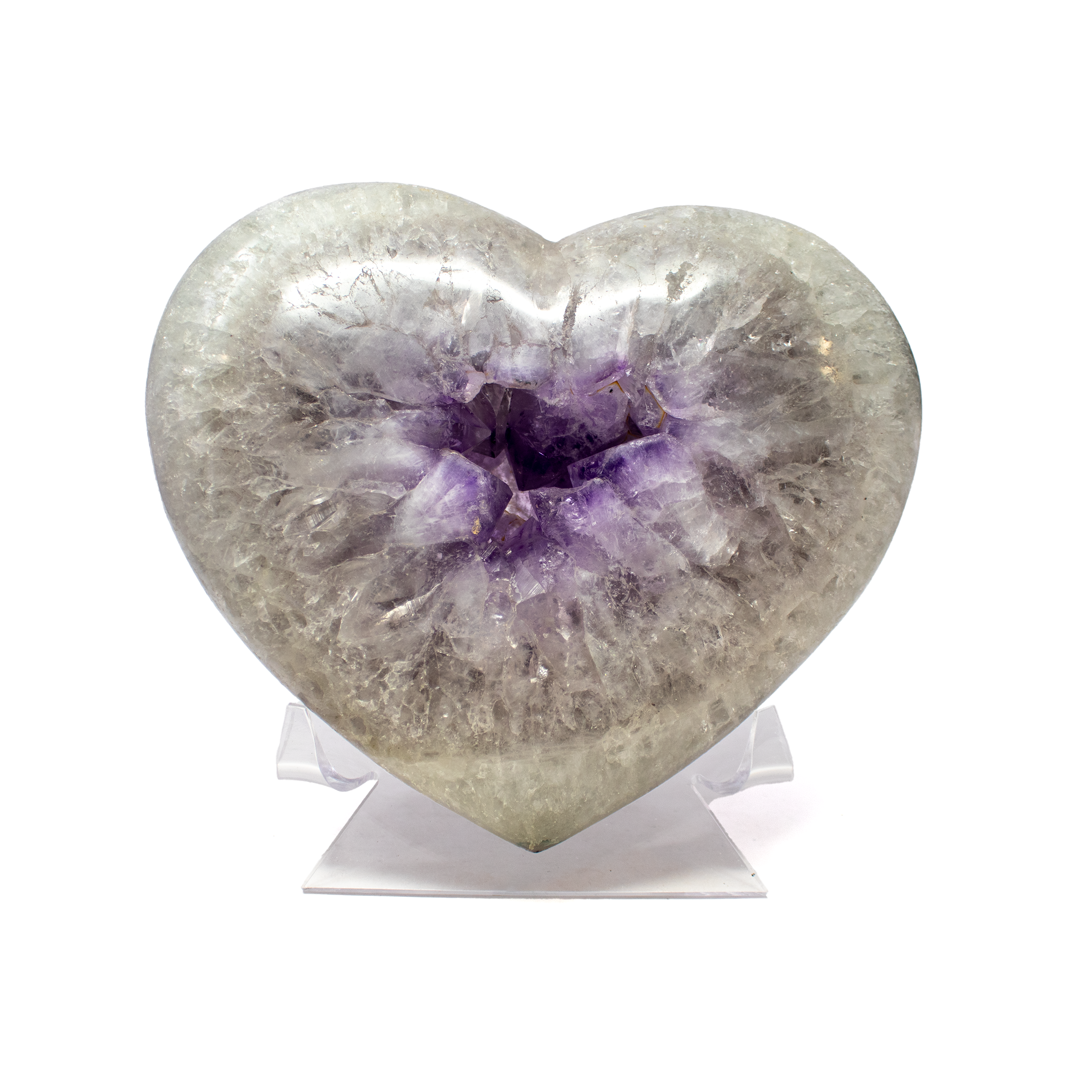 The Polished Quartz Heart with Amethyst Crystal Center from Brazil is a radiant fusion of clarity and color, crafted to showcase the natural harmony between two revered minerals. Smooth and luminous, the clear quartz has been carved into a heart, its polished surface reflecting light with serene brilliance. At its core lies a vivid amethyst crystal pocket—its deep violet hue creating a mesmerizing contrast and drawing the eye inward.Mounted on a transparent Lucite stand, the heart appears to float in midair, emphasizing its form and allowing unobstructed views from every angle. Clear quartz is celebrated for its purifying energy, while amethyst is revered for its calming and spiritual qualities—together they form a piece that is both visually striking and energetically balanced. Ideal for collectors and crystal enthusiasts alike, this sculpture is a testament to Brazil’s geological beauty and the refined artistry that reveals it. Polished Quartz Heart with Amethyst Crystal Center from Brazil on Lucite Stand