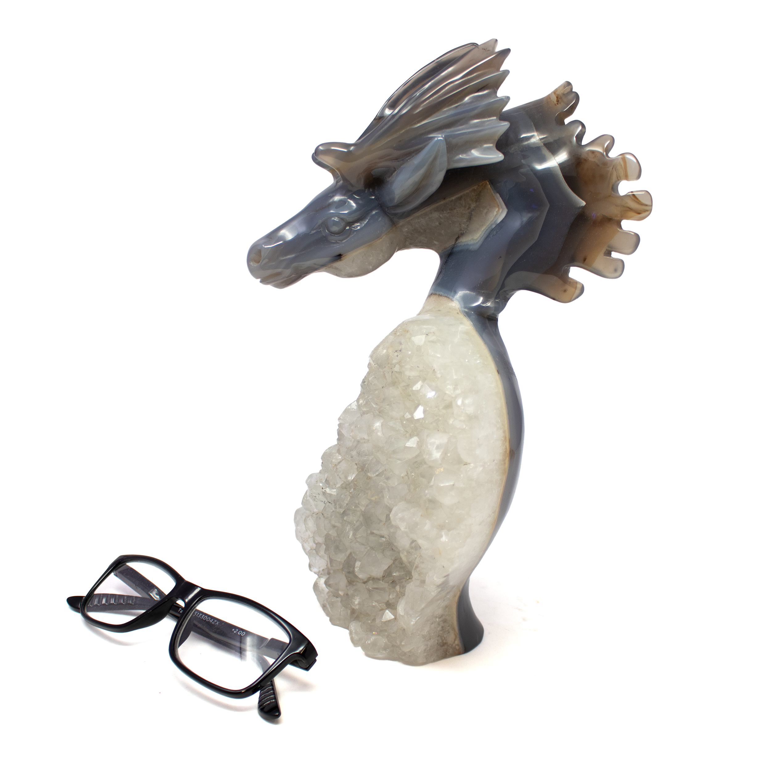 The A+ Agate Geode Moose Carving on Natural Geode Base unites refined craftsmanship with nature’s raw elegance in a singular, breathtaking sculpture. Expertly hand-carved in China from Brazilian agate, the moose’s lifelike form emerges from the geode’s shimmering crystal matrix, each curve and contour highlighted by the stone’s vibrant natural banding. From deep amethyst purples to soft earth tones, no two are alike—each one a one-of-a-kind expression of the earth’s artistry.Anchored on a rugged, crystalline geode base that sparkles in the light, this sculpture blends wild majesty with polished sophistication. A statement piece for collectors and nature lovers alike, it transforms any space with grounded beauty and timeless presence. A+ Agate Geode Moose Carving on Natural Geode Base - All One Piece