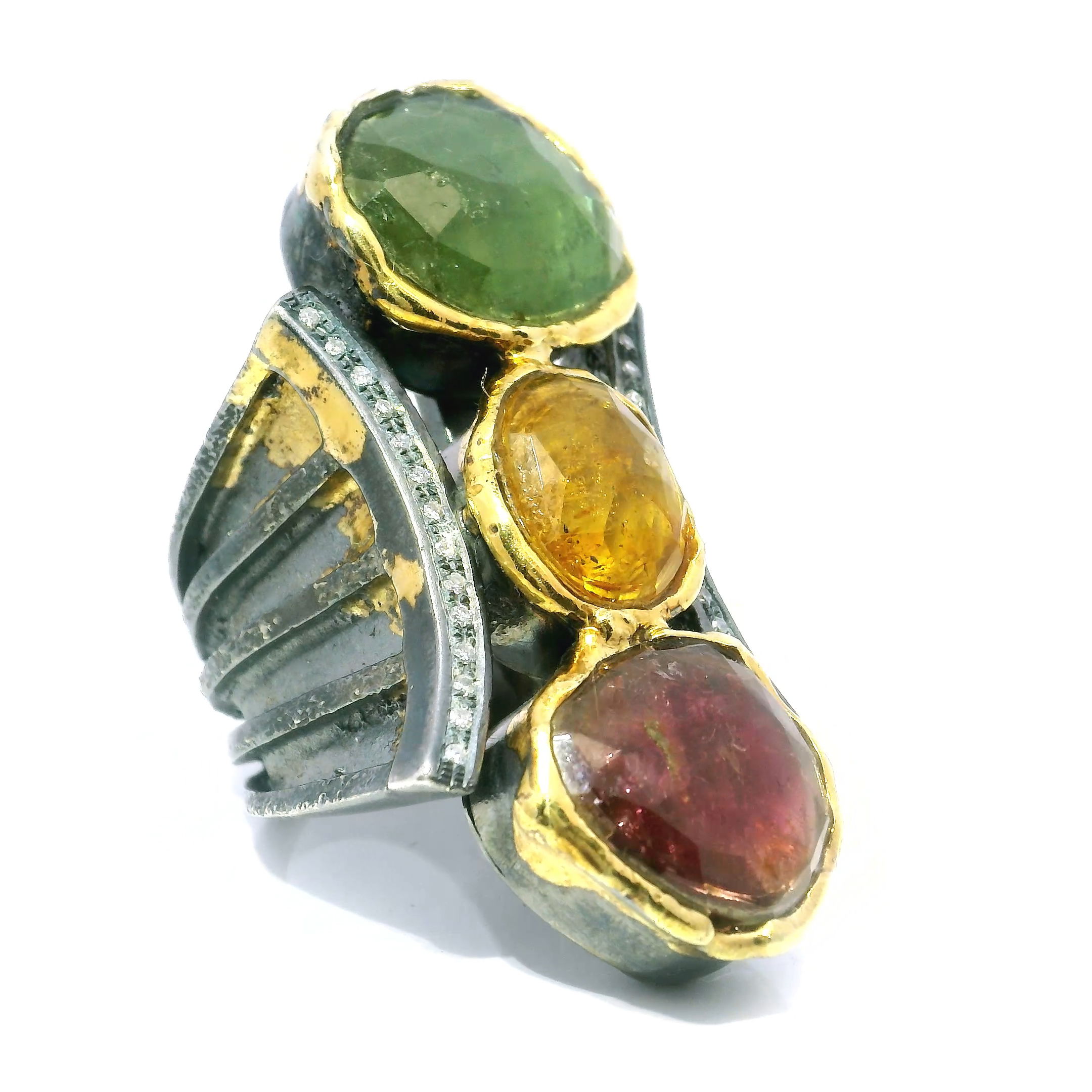 Add a radiant pop of color to your jewelry collection with this Multi-Color Tourmaline Ring in 925 Sterling Silver. Three bezel-set tourmaline cabochons—pink, golden, and green—gleam with rich, natural vibrancy, while delicate pave-set diamonds trace two graceful curves, enhancing the ring’s fluid silhouette.Touches of dripped gold provide contrast and modern flair, uniting the design in a harmonious balance of elegance and edge. Sized at 8.5, this one-of-a-kind statement ring is perfect for the woman who cherishes gemstone artistry and bold, sculptural beauty. Ideal for special occasions or refined daily wear, it’s a luminous celebration of individuality. Multi-Color Tourmaline Ring - Faceted Pink & Golden & Green Tourmaline Cabochons with 2 Curved Lines of Single Row Pave Diamonds & Dripped Gold Accents Bezel Set in 925 Sterling Silver sz8.5