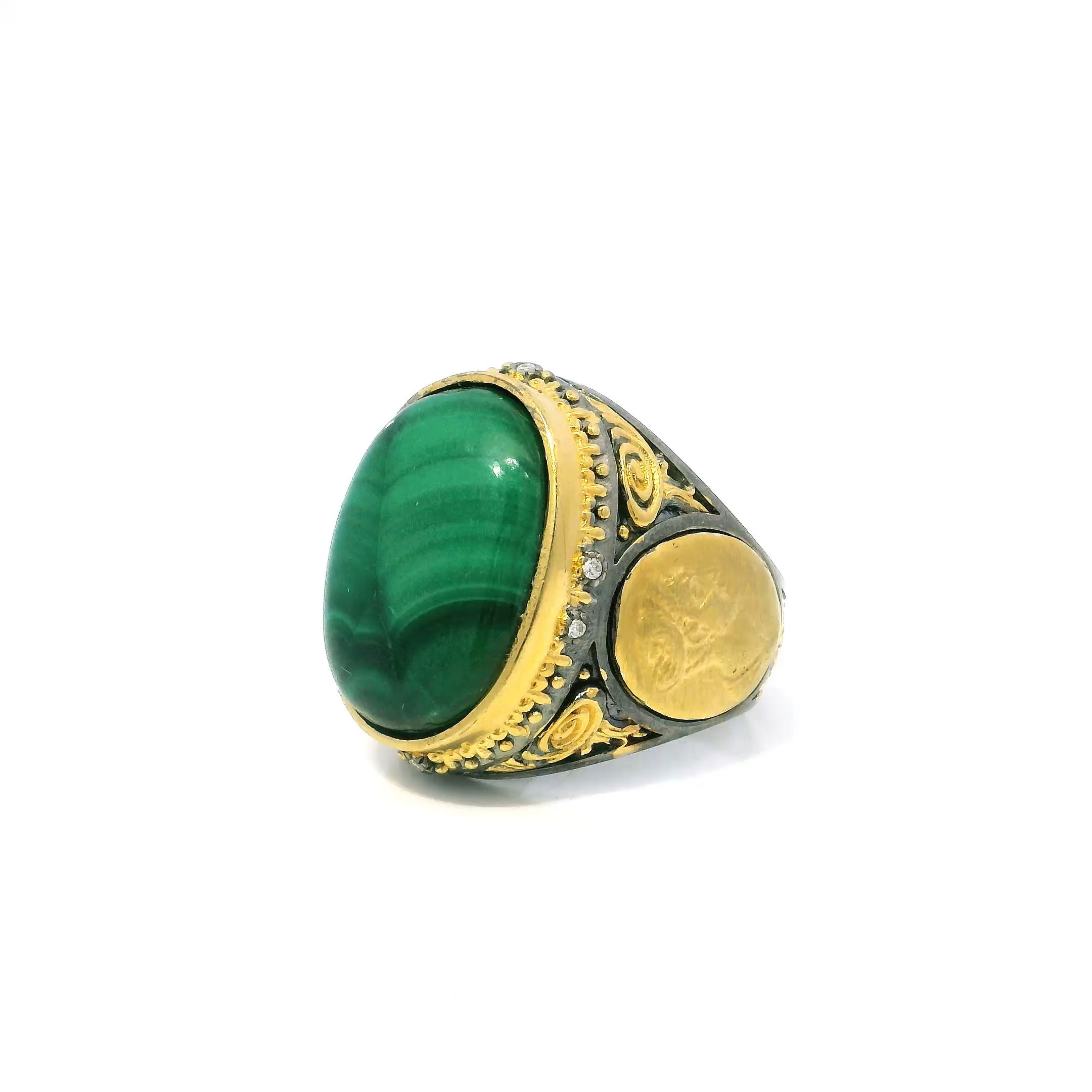 Elevate your style with this exquisite Malachite Ring, featuring a striking oval cabochon centerpiece set in lustrous 925 sterling silver. The deep green hues of natural malachite are beautifully accented by six sparkling diamonds, adding a touch of brilliance.Gold side coin details and intricate beaded accents encircle the bezel, lending a luxurious, artistic finish. Perfectly sized at 9, this unique ring is a sophisticated statement piece for those who cherish elegance and individuality. Malachite Ring - Oval Cabochon & 6 Diamonds with Gold Side Coin & Beaded Details Bezel Set in 925 Sterling Silver sz9
