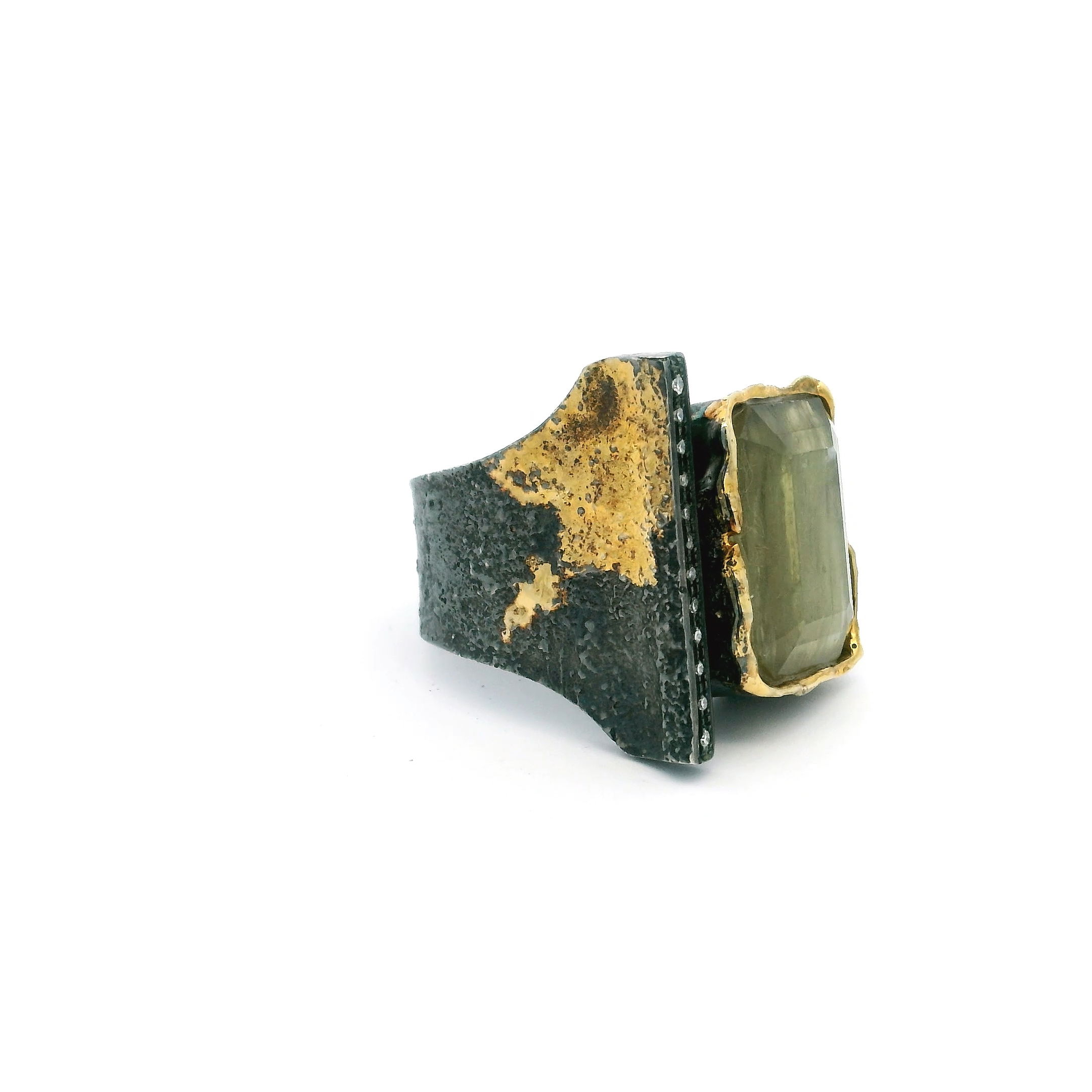 Elevate your style with this exquisite Zultanite Ring, featuring a captivating faceted square Zultanite gemstone bezel-set in lustrous 925 sterling silver. Dripped gold accents frame the center stone with a modern, fluid elegance, while the stone’s natural color-shifting properties add depth and intrigue to every glance.The open band is adorned with a single row of dazzling pavé diamonds, offering refined sparkle and a balanced contrast to the warm shimmer of Zultanite. Designed in size 7, this ring is a timeless piece that blends artistic design with luxurious materials—perfect for any jewelry collection seeking distinction and brilliance. Zultanite Ring - Faceted Square on Open Band with Single Row Pave Diamonds & Dripped Gold Accents Bezel Set in 925 Sterling Silver sz7