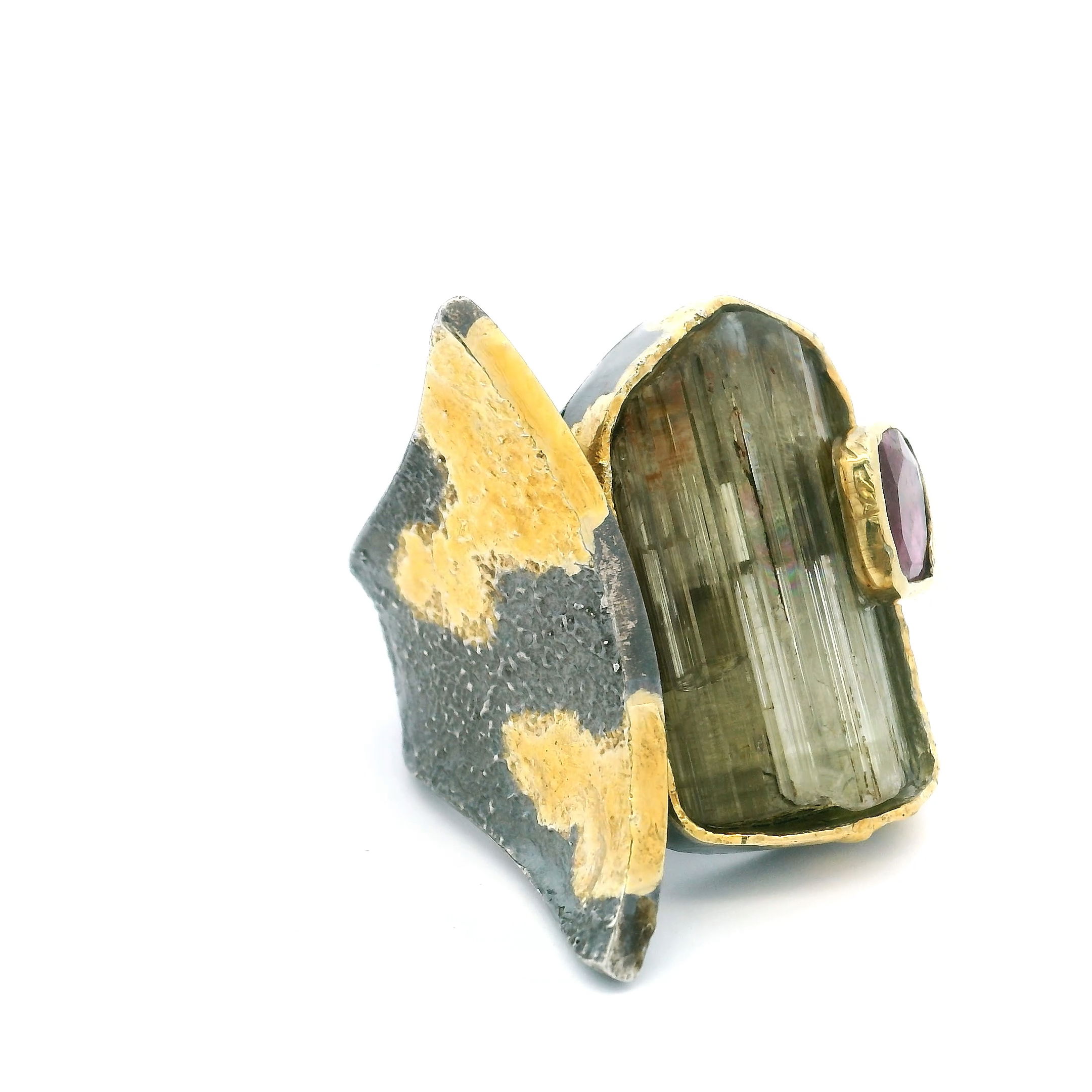 The Zultanite Ring is a captivating fusion of elegance and artistry, showcasing a mesmerizing rectangular freeform Zultanite gemstone known for its chameleon-like color shift in different lighting. A faceted pink tourmaline square complements the centerpiece, adding a vibrant pop of color and visual contrast.Both stones are bezel-set in polished 925 sterling silver, while dripped gold accents wrap the open band with a modern, sculptural edge. Designed in size 8, this piece blends contemporary luxury with the natural magic of color-shifting gemstones—perfect for any collection that values bold design and refined detail. Zultanite Ring - Rectangular Freeform & Faceted Pink Tourmaline Square on Open Band with Dripped Gold Accents Bezel Set in 925 Sterling Silver sz8