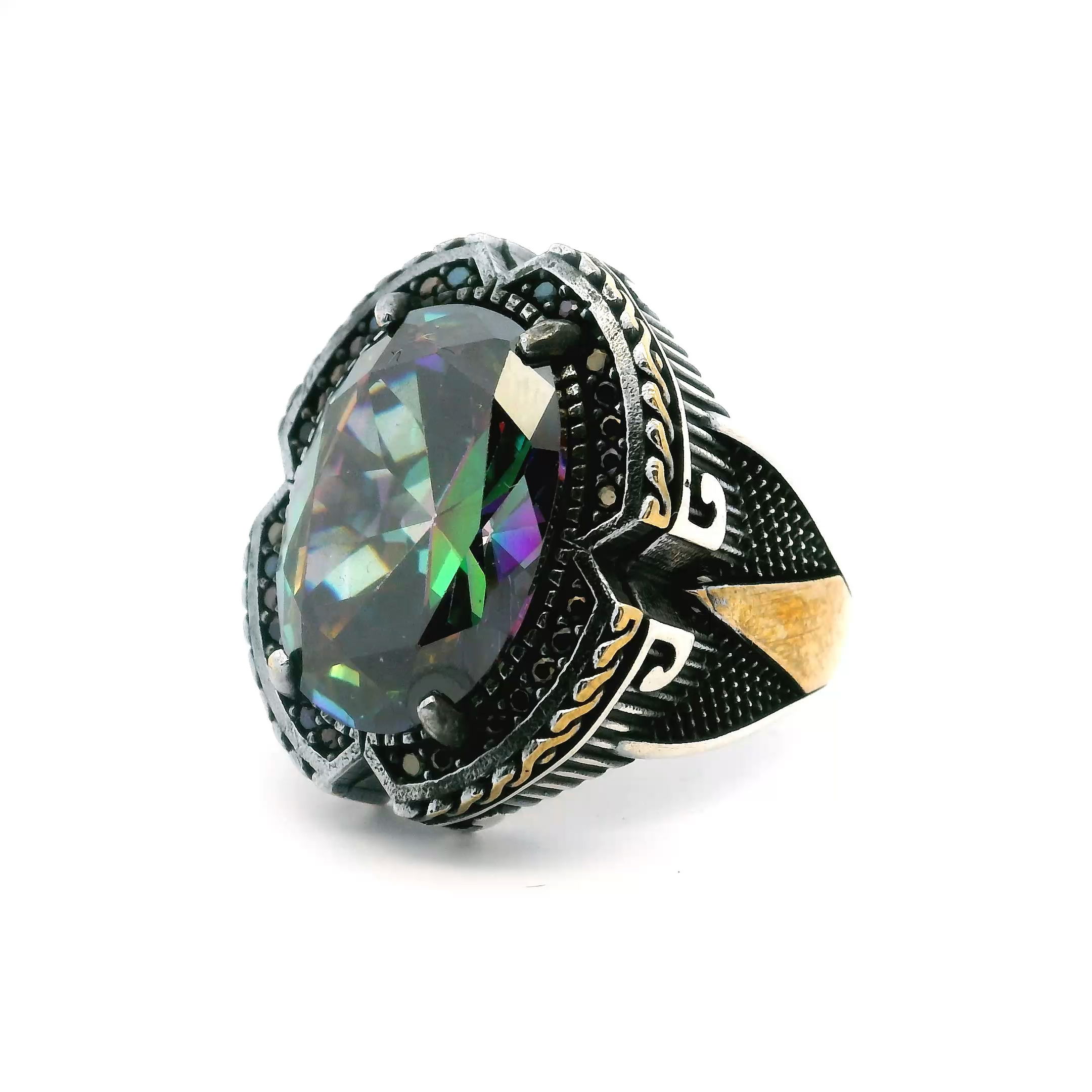Unveil a new level of brilliance with this striking Mystic Topaz Ring, crafted for the modern man. The centerpiece is a mesmerizing faceted oval mystic topaz, radiating iridescent hues that shift with every glance.A halo of shimmering black nanostones in a refined pavé setting frames the stone, while distinctive triangular notches on each prong add both security and style. Forged from solid 925 sterling silver, the band is accented with a lavish gold vermeil rope detail, blending classic elegance with contemporary edge. Sized at 10.5, this ring is perfect for those who value exceptional craftsmanship and eye-catching sophistication. Mystic Topaz Ring - Faceted Oval with Pave Black Nanostones & Triangular Notches Prong Set in 925 Sterling Silver with Gold Vermeil Rope Accent sz10.5