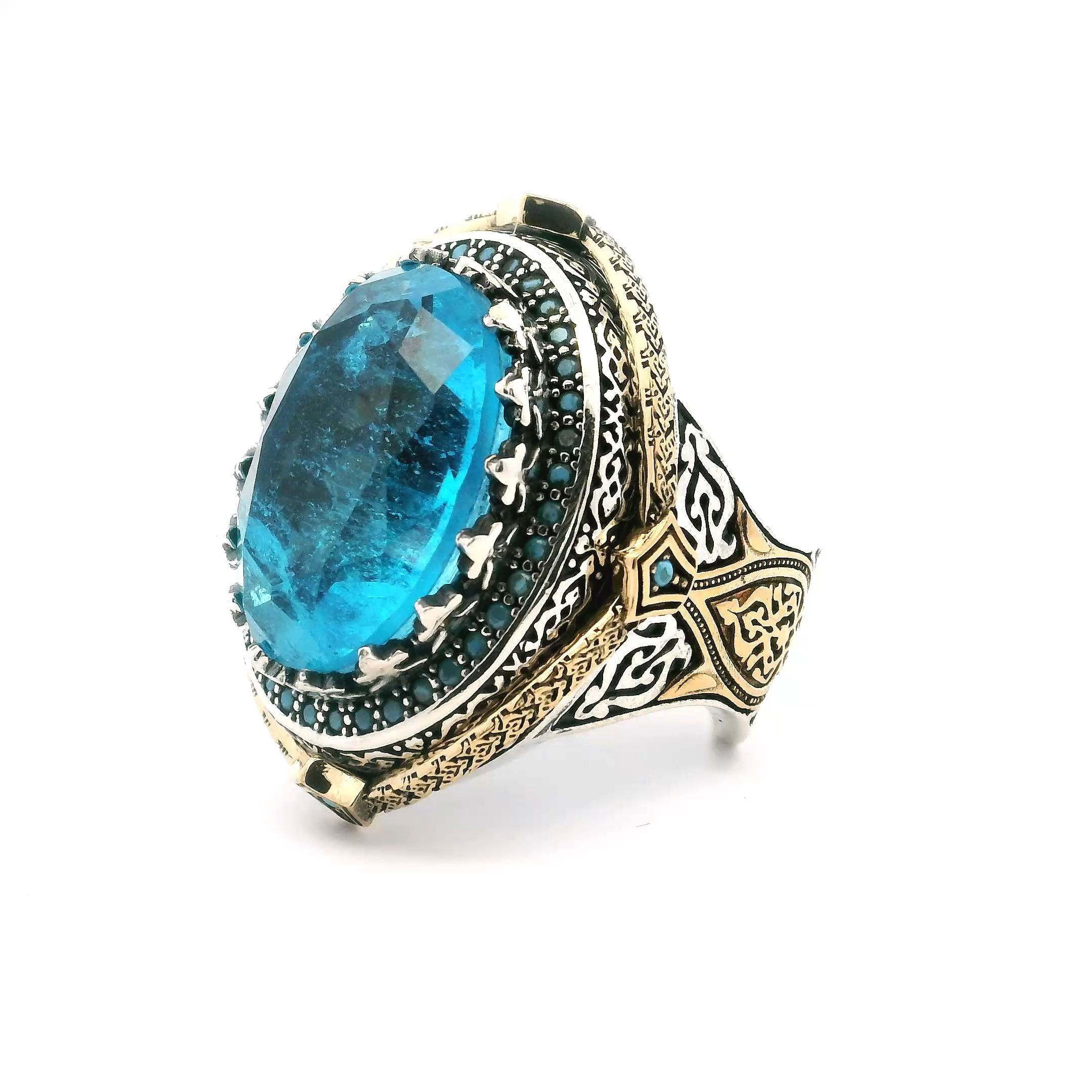 Elevate your style with this striking Blue Topaz Ring, crafted for the modern man. A faceted oval blue topaz takes center stage, secured in a distinctive sawtooth setting that demands attention.A single row of vibrant turquoise nanostones is pave-set around the gemstone, adding a bold pop of color and refined detail. Cast in premium 925 sterling silver with luxurious gold vermeil accents, this size 9 ring blends artistry and sophistication into a captivating statement piece for any collection. Blue Topaz Ring - Faceted Oval in Designer Sawtooth Setting with Single Row Pave Turquoise Nanostones in 925 Sterling Silver with Gold Vermeil Accents sz9