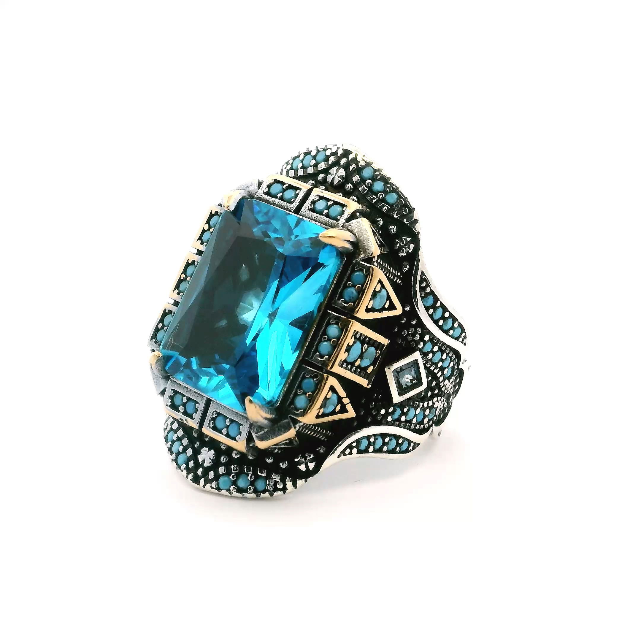 Make a bold statement with this striking Blue Topaz Ring for men, crafted in 925 sterling silver and finished with rich gold vermeil. The size 11 ring showcases a faceted rectangular blue topaz centerpiece, flanked by two prong-set blue topaz squares that amplify its brilliance.Turquoise nanostone inlays and beaded turquoise accents bring a sophisticated pop of color and intricate detail. Exclusive and eye-catching, this ring perfectly blends artful design with modern masculinity, ideal for the man who values unique, handcrafted jewelry. Blue Topaz Ring - Faceted Rectangle with Turquoise Nanostones & 2 Blue Topaz Squares Prong Set in 925 Sterling Silver with Gold Vermeil & Beaded Turquoise Accents sz11