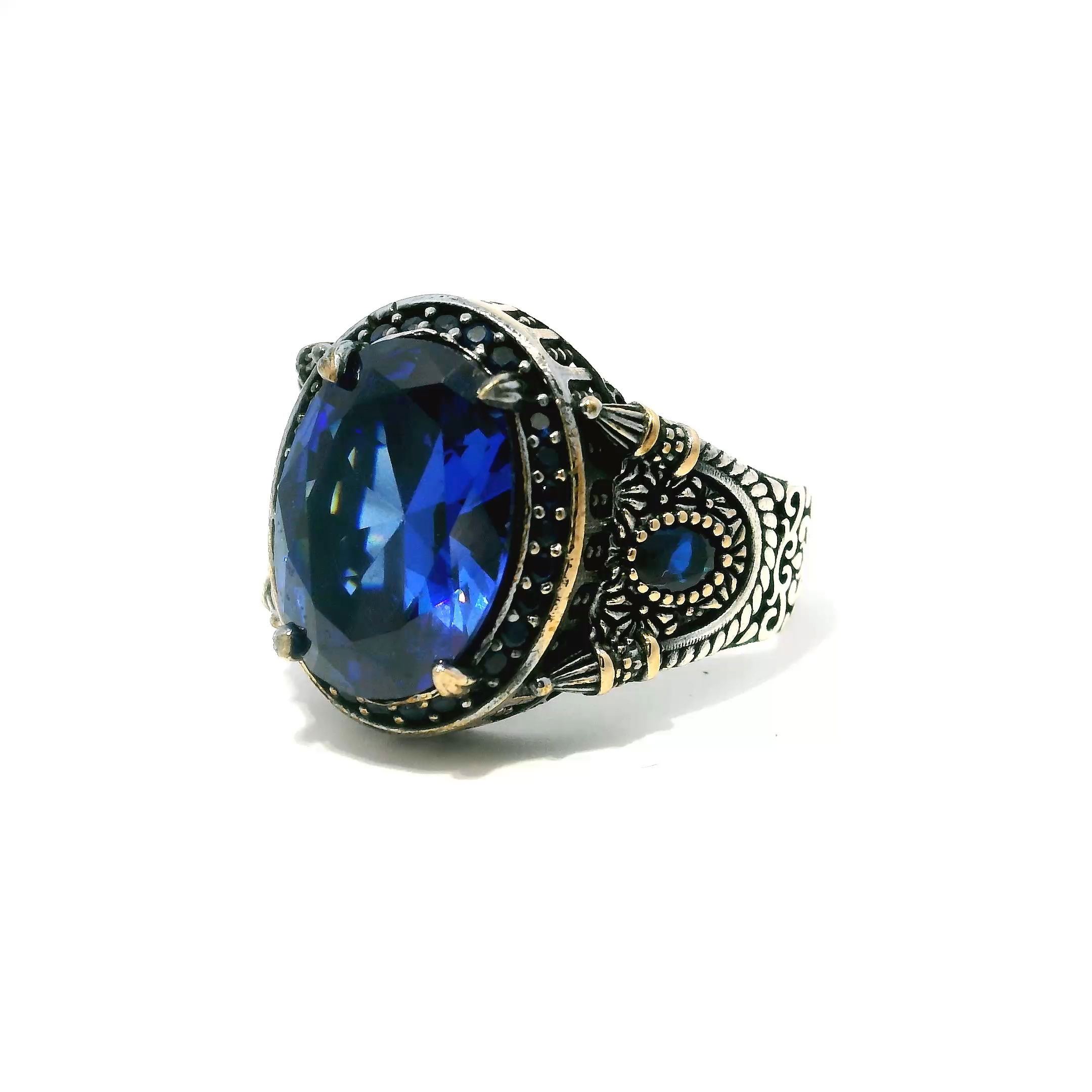 Elevate your style with this striking Sapphire Ring, expertly crafted for men who appreciate sophistication and bold design. At its center, a faceted oval sapphire glows with deep, luminous blue—flanked by two smaller faceted sapphires for balanced brilliance. A row of pavé-set sapphire nanostones surrounds the trio, enhancing the ring’s refined sparkle.The band, forged in solid 925 sterling silver, is finished with rich gold vermeil accents that add warmth and contrast to the cool sapphire tones. Sized at 10.25, this ring offers a seamless blend of comfort and luxury—an essential statement piece for the modern gentleman’s collection. Sapphire Ring - Faceted Oval with Single Row Pave Sapphire Nanostones & 2 Faceted Sapphire Side Ovals Prong Set in 925 Sterling Silver with Gold Vermeil Accents sz10.25