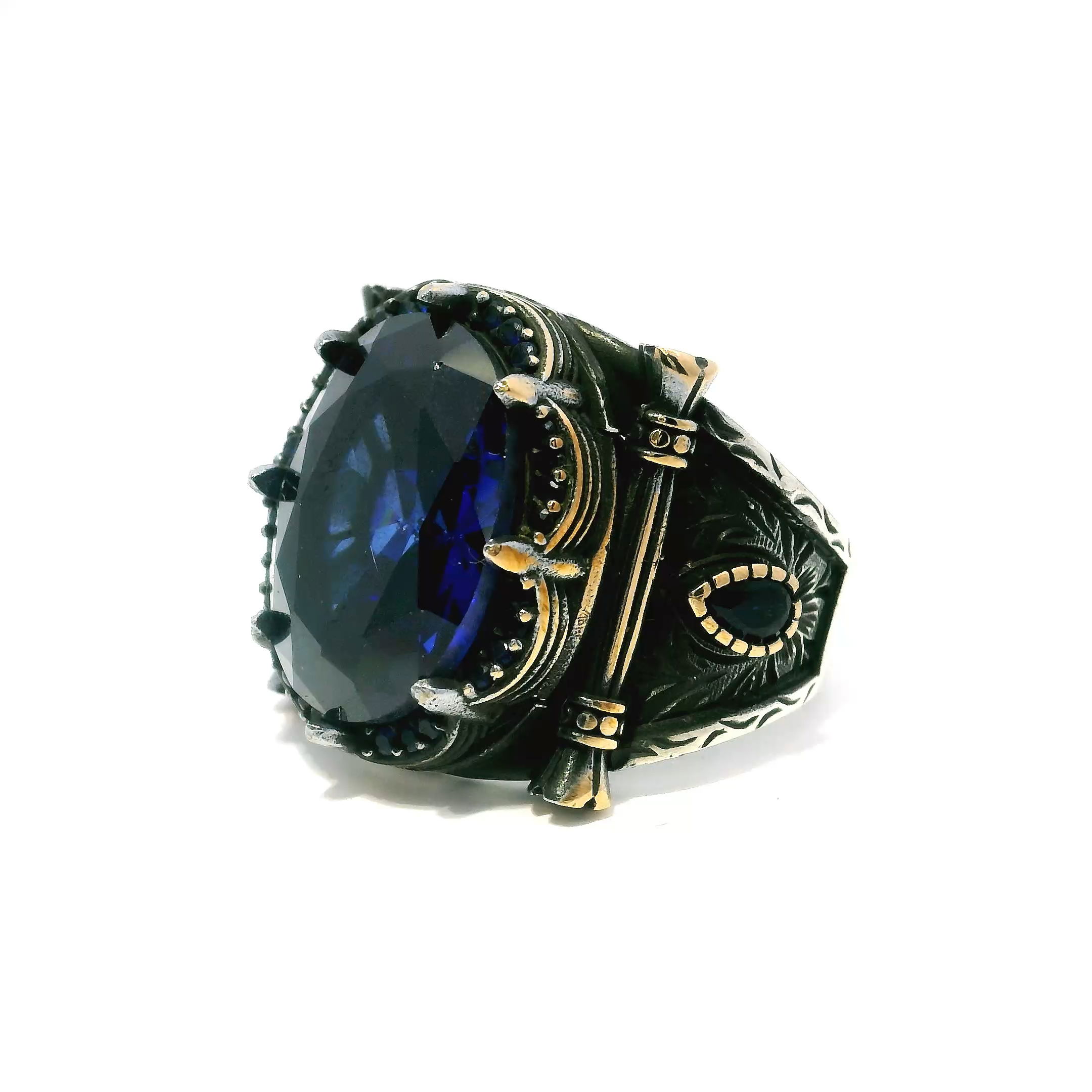 Elevate your style with this striking Sapphire Ring, crafted for the discerning gentleman. The centerpiece is a brilliant faceted oval sapphire, held securely in regal crown prongs and encircled by a row of pavé-set sapphire nanostones that add intense radiance and depth.Two faceted pear-shaped sapphires flank the center, enhancing the ring’s dynamic design. Sculpted from solid 925 sterling silver and finished with rich gold vermeil accents, the band blends durability with refined elegance. Sized at 11.5, this bold ring is the perfect statement for special occasions or adding distinction to your everyday look. Sapphire Ring - Faceted Oval with Single Row Pave Sapphire Nanostones & 2 Faceted Sapphire Side Pears with Crown Prong Setting in 925 Sterling Silver with Gold Vermeil Accents sz11.5