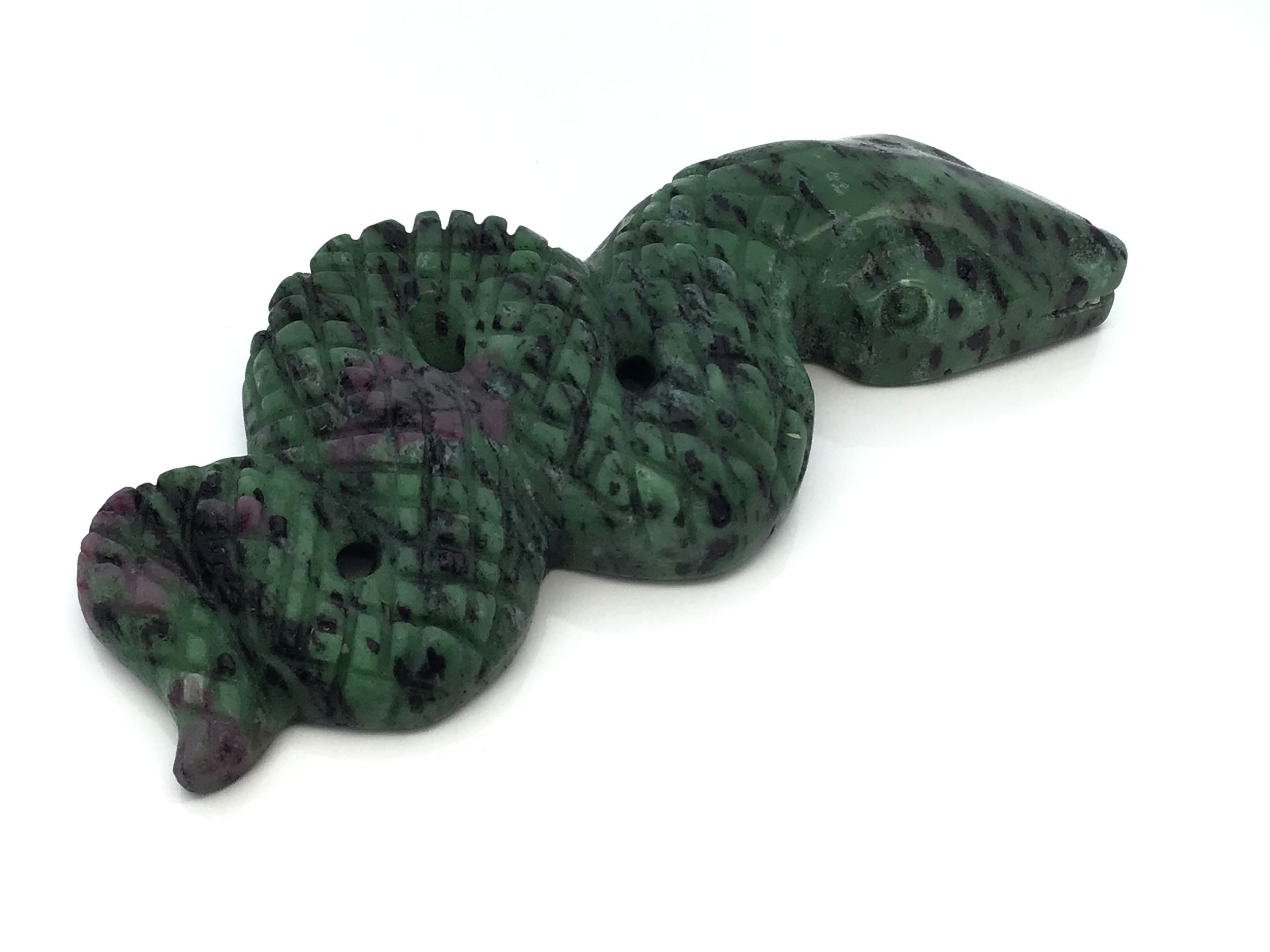 A fusion of fierce elegance and natural power, the Ruby Zoisite 4" Snake Ready-to-Strike Carving captures the serpent’s coiled intensity in vivid, energetic stone. Hand-carved from genuine ruby zoisite, this compact sculpture balances the grounding green of zoisite with fiery crimson bursts of ruby—each piece a rare, one-of-a-kind blend of color and meaning.Poised in a dynamic strike, the snake embodies transformation, protection, and inner strength. Its sinuous form is polished to a smooth finish, revealing the gemstone’s wild, organic beauty and igniting a visual contrast between calm and passion. At approximately 4 inches, it makes a bold addition to altars, crystal grids, or curated décor. Ruby Zoisite 4" Snake Ready-to-Strike Carving