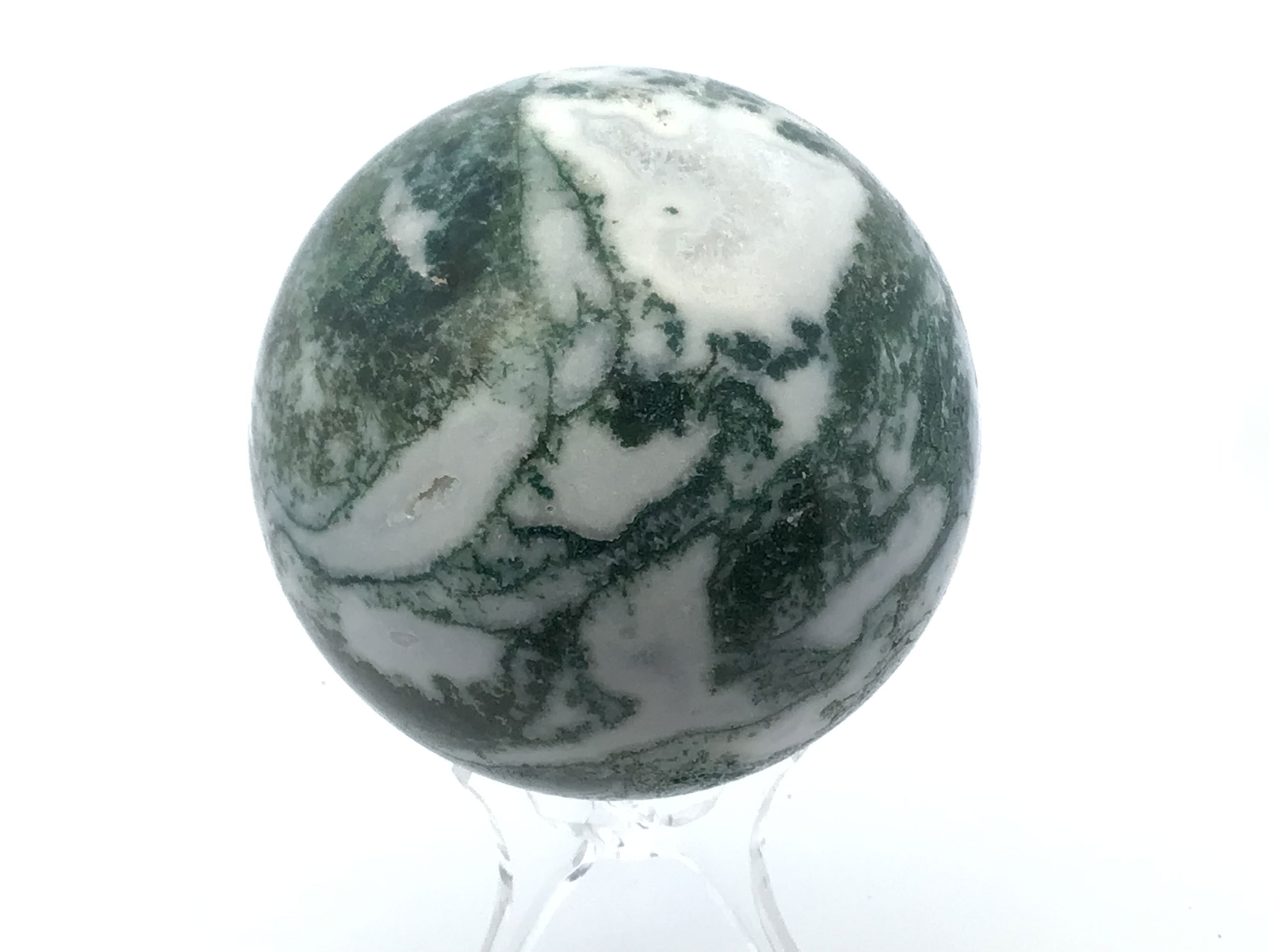 Polished to a smooth, radiant sphere, this genuine Moss Agate captures enchanting forest-green inclusions and earthy patterns, each piece uniquely reflecting nature’s artistry. Resting on a minimalist Lucite stand, it offers a modern display that complements any setting—from meditation spaces to office desks.Cherished for its grounding and nurturing qualities, Moss Agate inspires balance, renewal, and a deeper connection to the natural world. This sphere is an elegant addition to crystal collections or a meaningful gift for those drawn to earth’s tranquil energy. Moss Agate Sphere with Lucite Stand