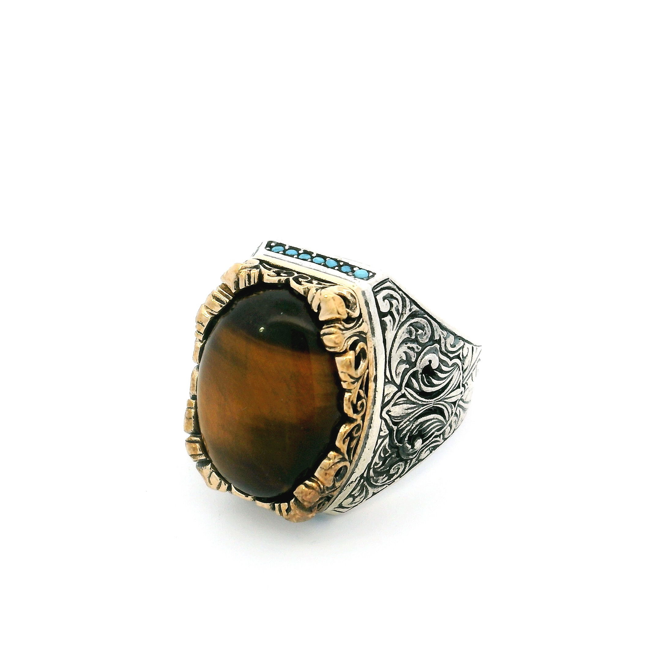 Command attention with this Tigers Eye Ring, crafted for the modern man who values bold elegance. The centerpiece is a captivating oval cabochon of genuine tiger’s eye, showcasing rich golden-brown bands that shimmer with every movement. Set in a durable yet luxurious gold vermeil bezel over 925 sterling silver, the design is elevated by a striking row of vibrant turquoise nanostones crowning the bezel’s top and bottom, offering vivid contrast and artisanal flair. Sized at 12 for a comfortable fit, this ring embodies strength, protection, and individuality—making it a sophisticated statement piece perfect for any occasion. Tigers Eye Ring - Oval Cabochon with Single Row Pave Turquoise Nanostones on Top & Bottom Bezel Set in Fancy Gold Vermeil with 925 Sterling Silver sz12