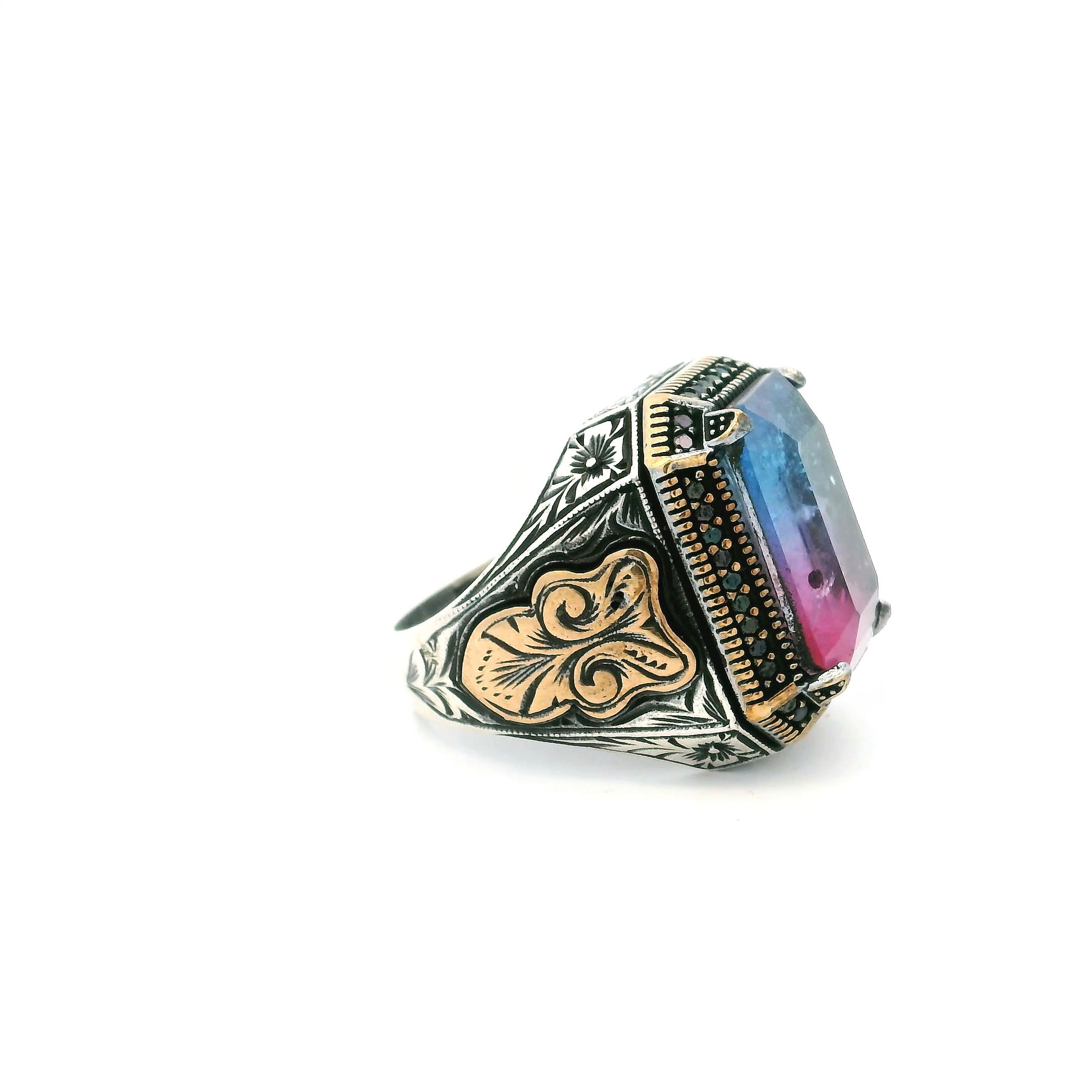 Discover striking sophistication with the Tourmaline Doublet Ring, a bold fusion of color, contrast, and craftsmanship. At its core, a brilliantly faceted blue and pink tourmaline doublet shimmers with multidimensional depth, catching light in every movement. A sleek row of black nanostones adds dramatic edge, while gold vermeil accents enrich the polished 925 sterling silver band with warmth and refinement. Designed in size 10.75, this statement ring blends timeless elegance with modern energy—ideal for those who move through the world with style and intention. Tourmaline Doublet Ring - Faceted Blue & Pink Tourmaline Doublet with Single Row Pave Black Nanostones Prong Set in 925 Sterling Silver with Gold Vermeil Accents sz10.75