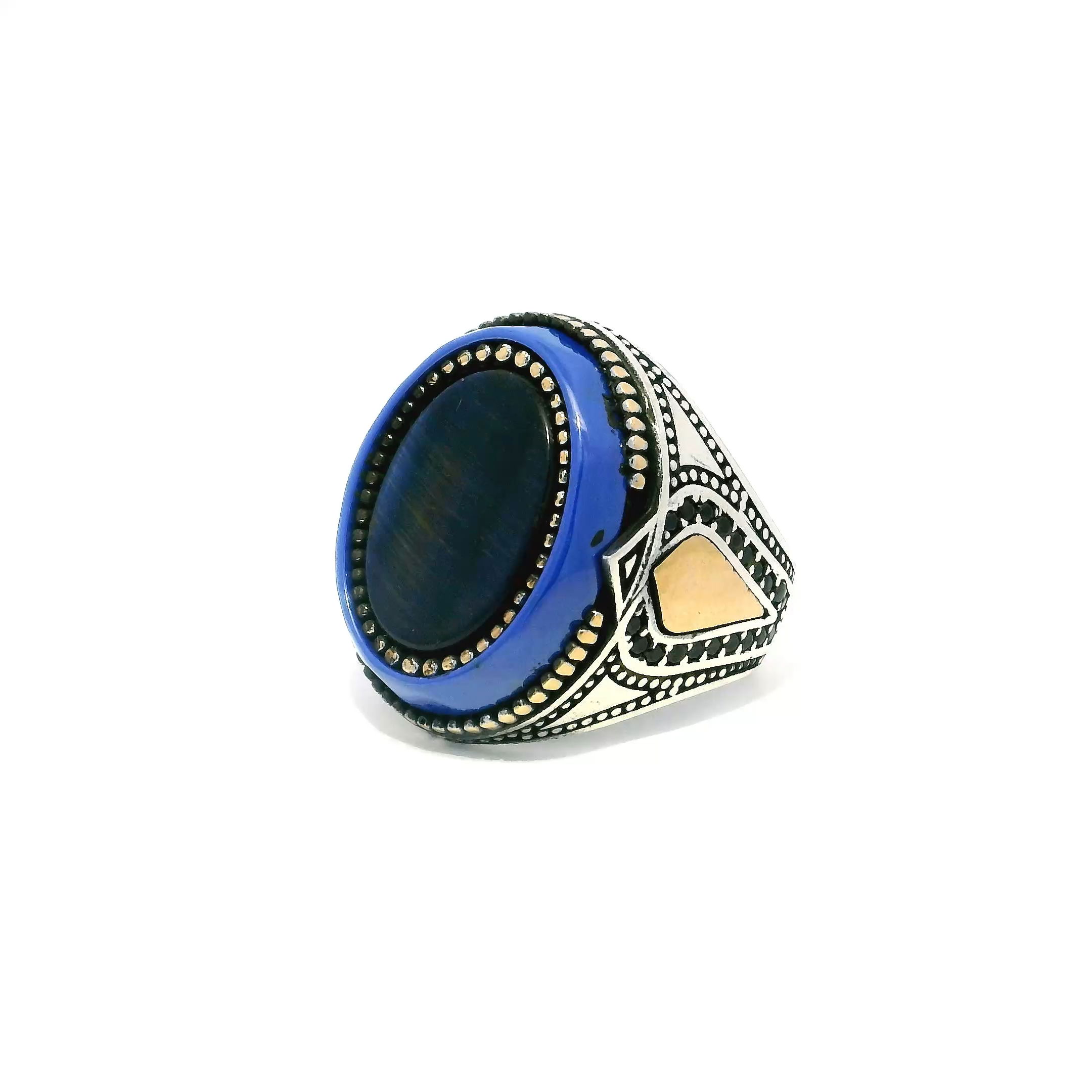 The Blue Tigers Eye Ring captures attention with its vibrant oval stone, expertly bezel-set in polished 925 sterling silver. Gold vermeil bead accents frame the striking blue hues, enhancing the stone’s natural shimmer, while black pavé nanostones along the band add a modern edge and sophisticated contrast. Sized at 8.25, this ring combines bold artistry with timeless elegance, perfect for those who seek unique, statement-making jewelry that elevates any look. Blue Tigers Eye Ring - Oval Flat Bezel Set with Gold Vermeil Bead Details & Larger Blue Oval & Black Pave Nanostones on Band in 925 Sterling Silver sz8.25