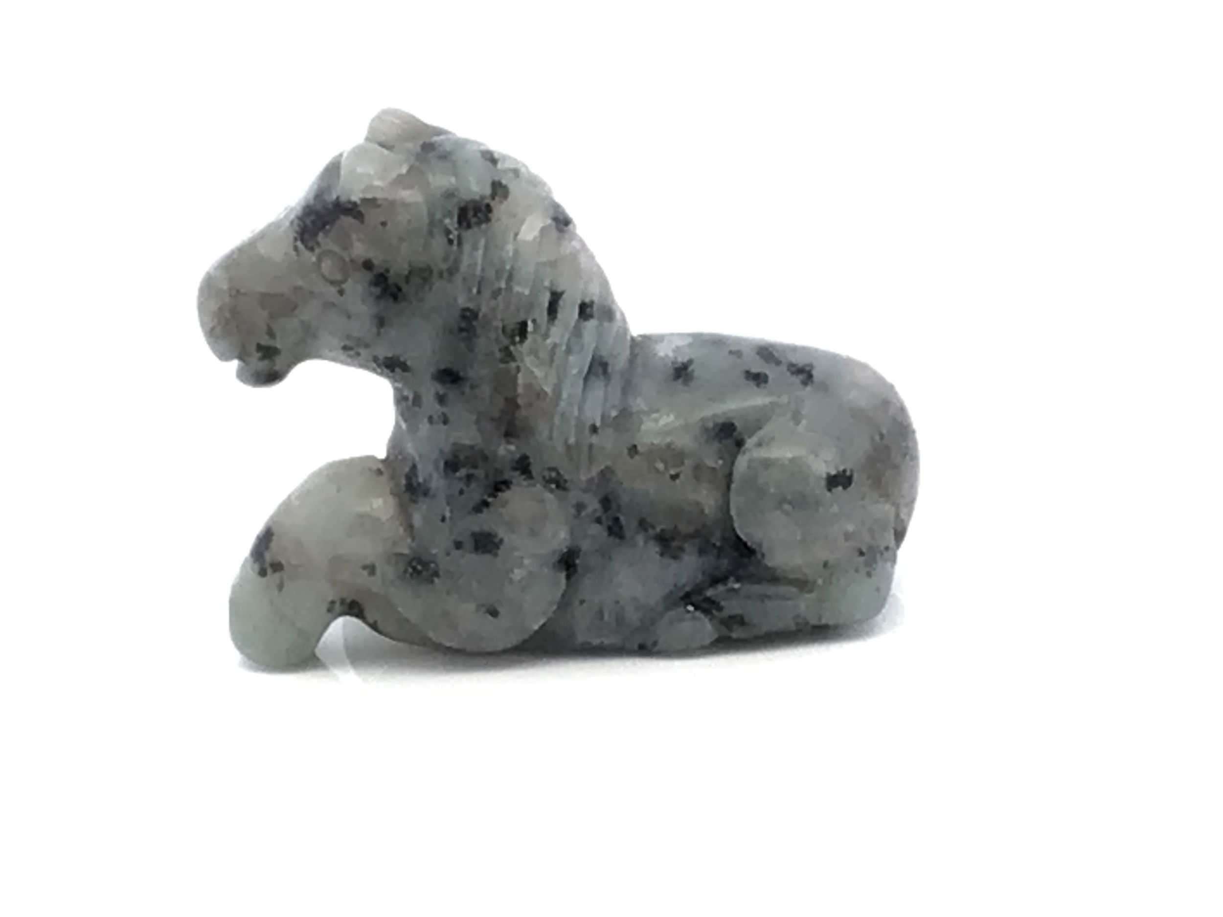 Gracefully poised in a moment of stillness, this hand-carved Kiwi Jasper Horse captures the gentle strength and tranquil soul of the natural world. Its unique blend of minty green, soft cream, and earthen brown flows across each curve, echoing meadow light and forest quiet. The horse, ever a symbol of freedom and spirit, rests in a laying pose that speaks to peace, resilience, and trust.A grounding presence for shelves, desks, or sacred spaces, this carving invites calm and connection wherever it’s placed—a serene companion for those who find beauty in wildness, and stillness in strength. Kiwi Jasper Horse Carving - Laying Down Posture