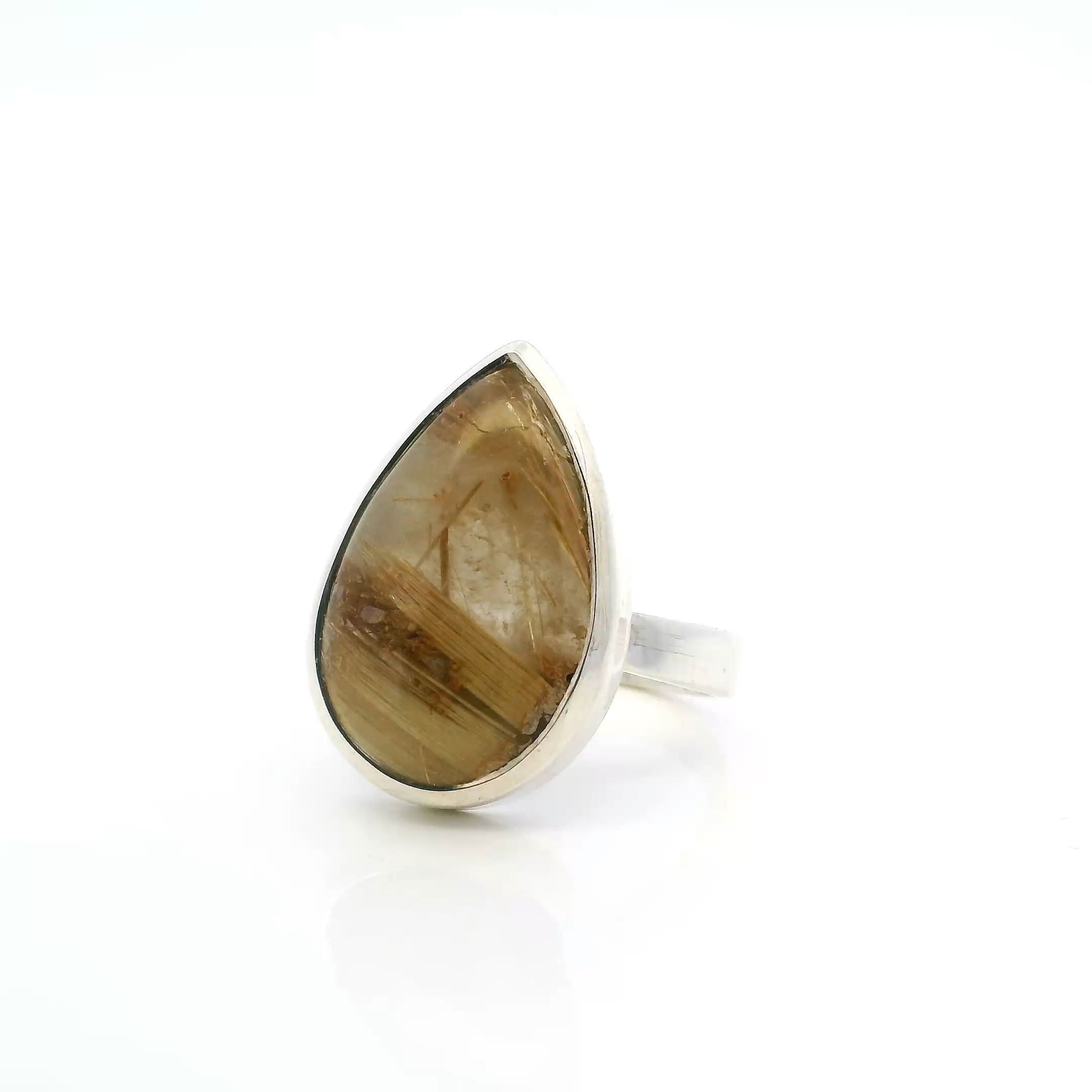 Elevate your look with this bold Golden Rutilated Quartz Ring, showcasing a pear-shaped cabochon streaked with dense, golden rutile concentrated at the base like captured sunlight. The sleek bezel setting in polished 925 sterling silver offers a clean, modern frame that lets the stone’s natural radiance shine. Sized at 10, this striking statement piece blends earthy elegance with refined design—perfect for those who appreciate rare gems and timeless simplicity. Golden Rutilated Quartz Ring - Pear Cabochon with Thick Gold Rutile on Bottom Half Bezel Set in Simple 925 Sterling Silver sz10